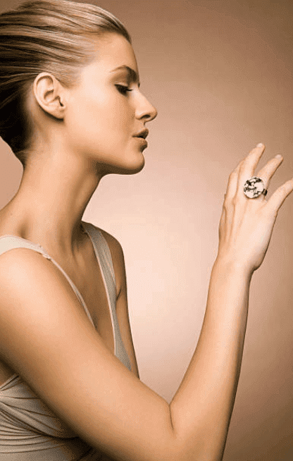 A young woman stares at her large diamond ring on her finger as she holds it in the air | Source: Getty Images