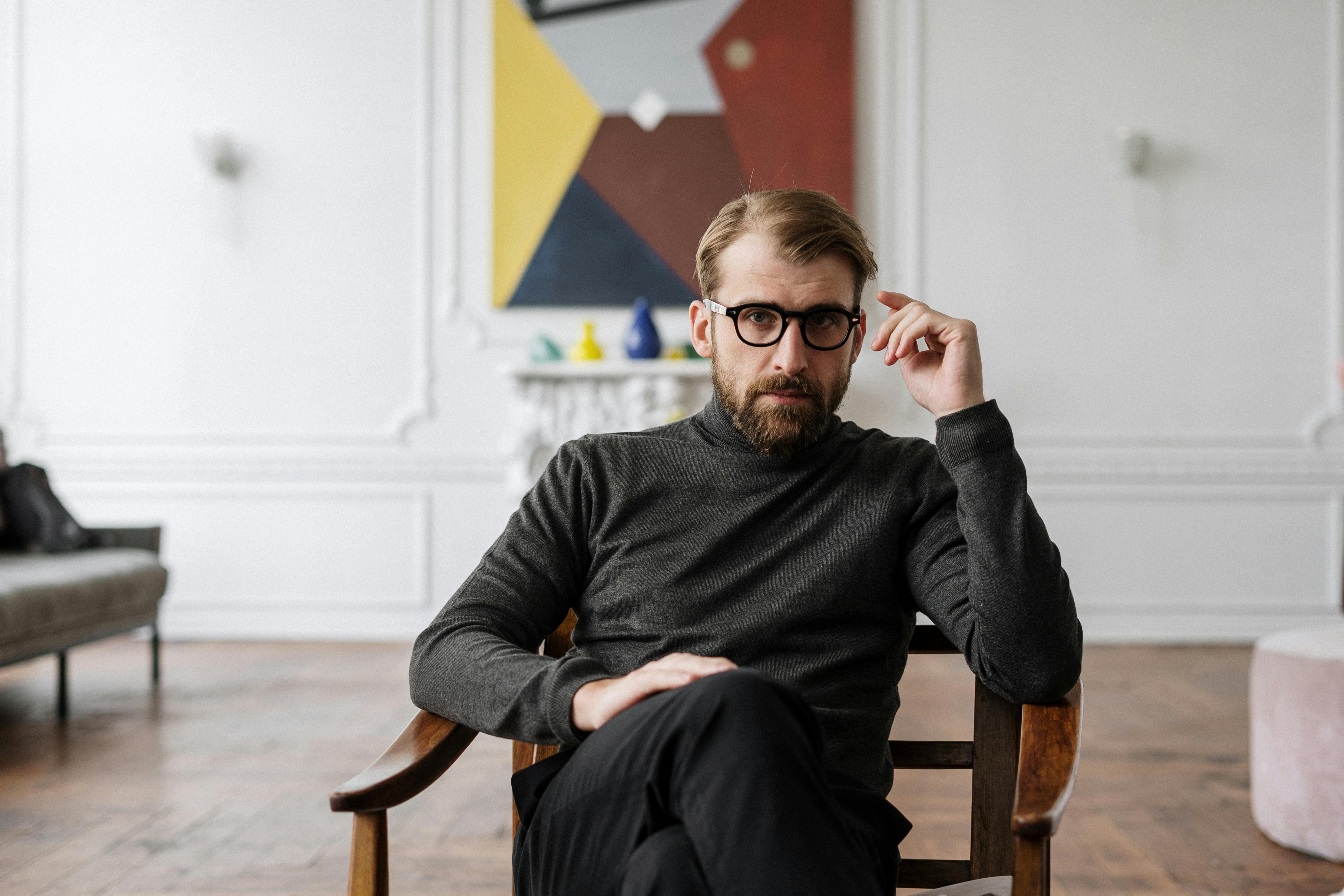 A serious-looking man sitting on a chair | Source: Pexels