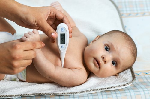 Una mujer le toma la temperatura al bebé con un termómetro. | Foto: Shutterstock