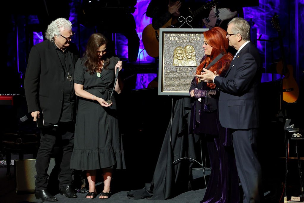 Ashley Judd [Center Left] accepts induction on behalf of Naomi Judd with Ricky Skaggs [Left], inductee Wynonna Judd [Center Right] and Kyle Young [Right] on May 01, 2022 in Nashville, Tennessee. | Source: Getty Images