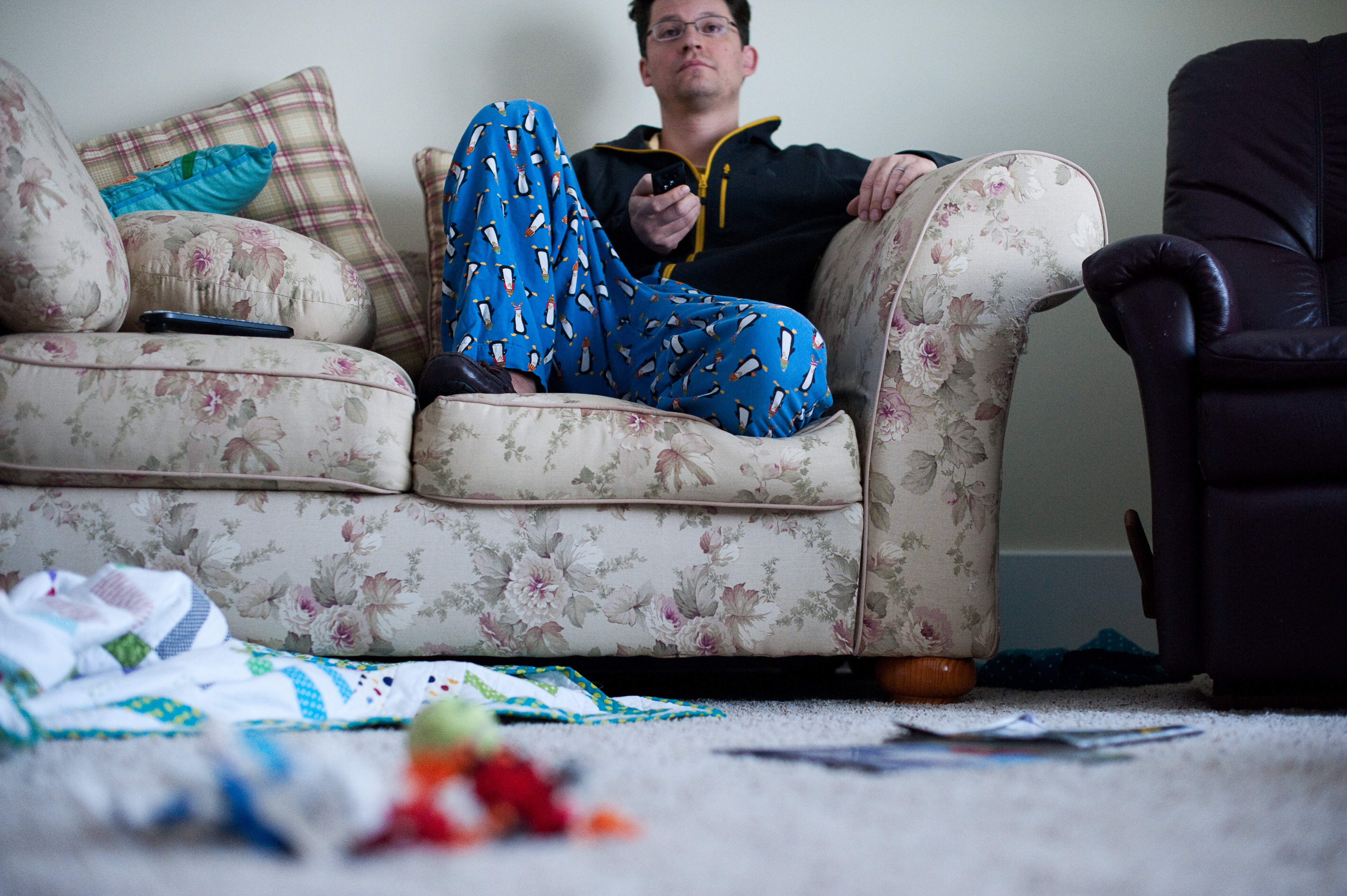 A lazy man sitting and watching television with a messy house | Source: Getty Images