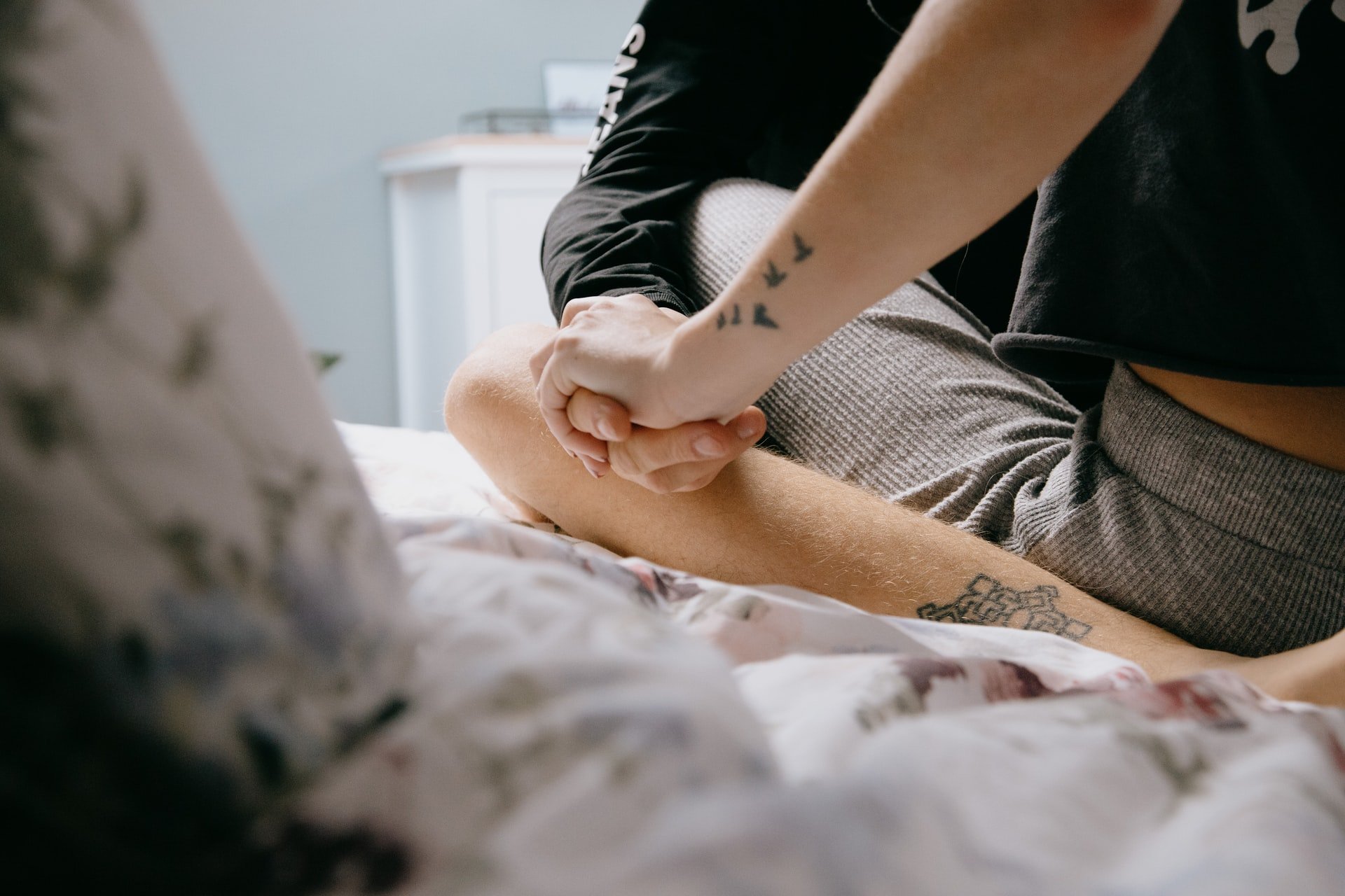 Couple sitting on bed holding hands | Source: Unsplash