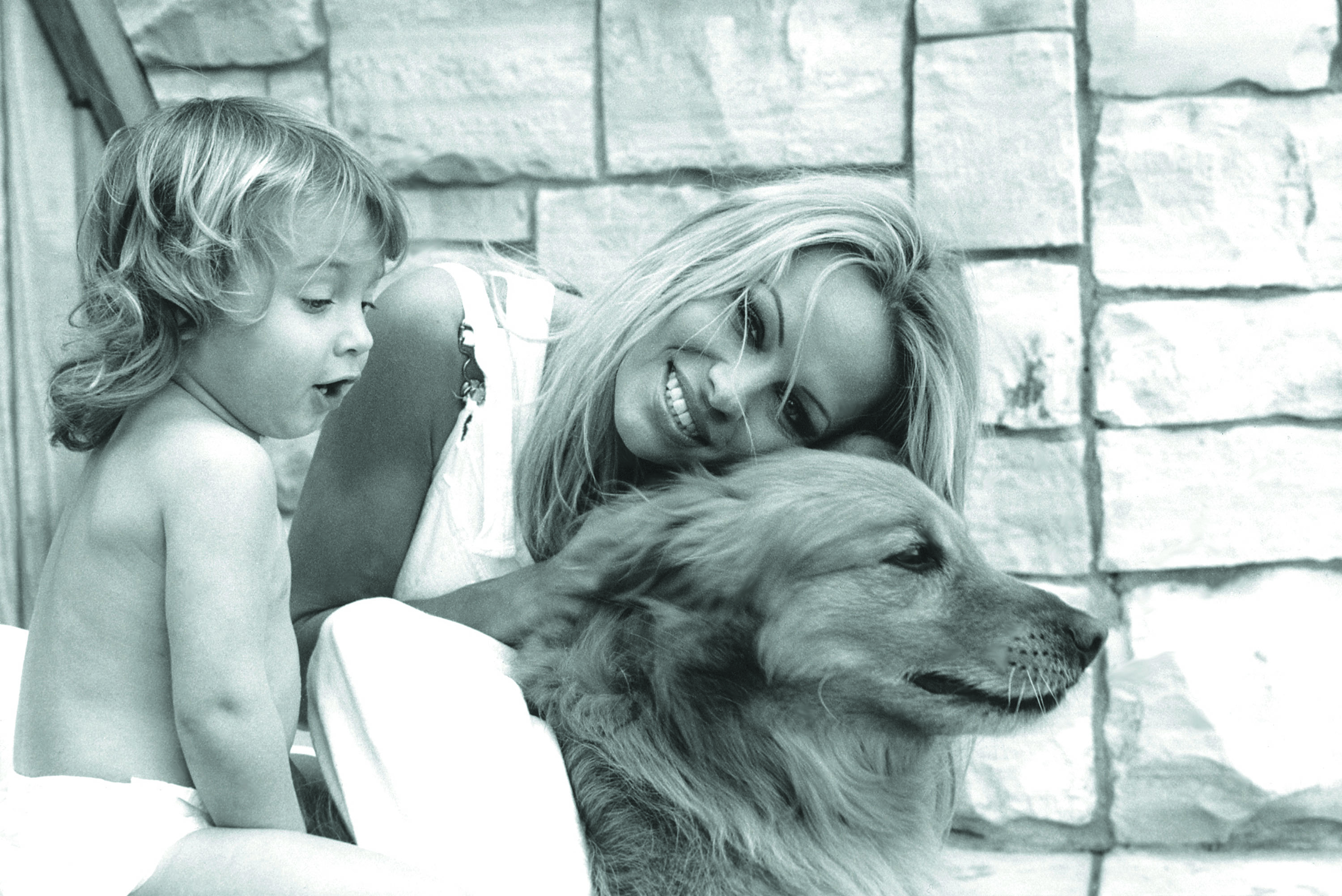 Pamela Anderson, Dylan Lee and her golden retriever Superstar pictured in the backyard of their home in Los Angeles, California on May 1, 2002 | Source: Getty Images
