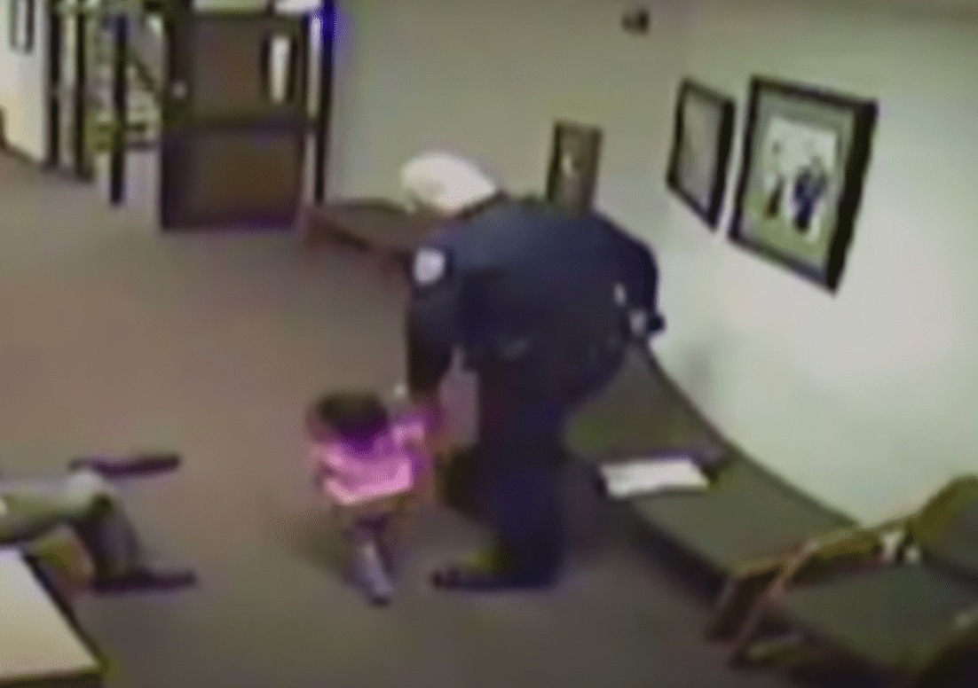 An officer looks after a little girl while her dad is busy in court. | Source: youtube.com/Inside Edition 