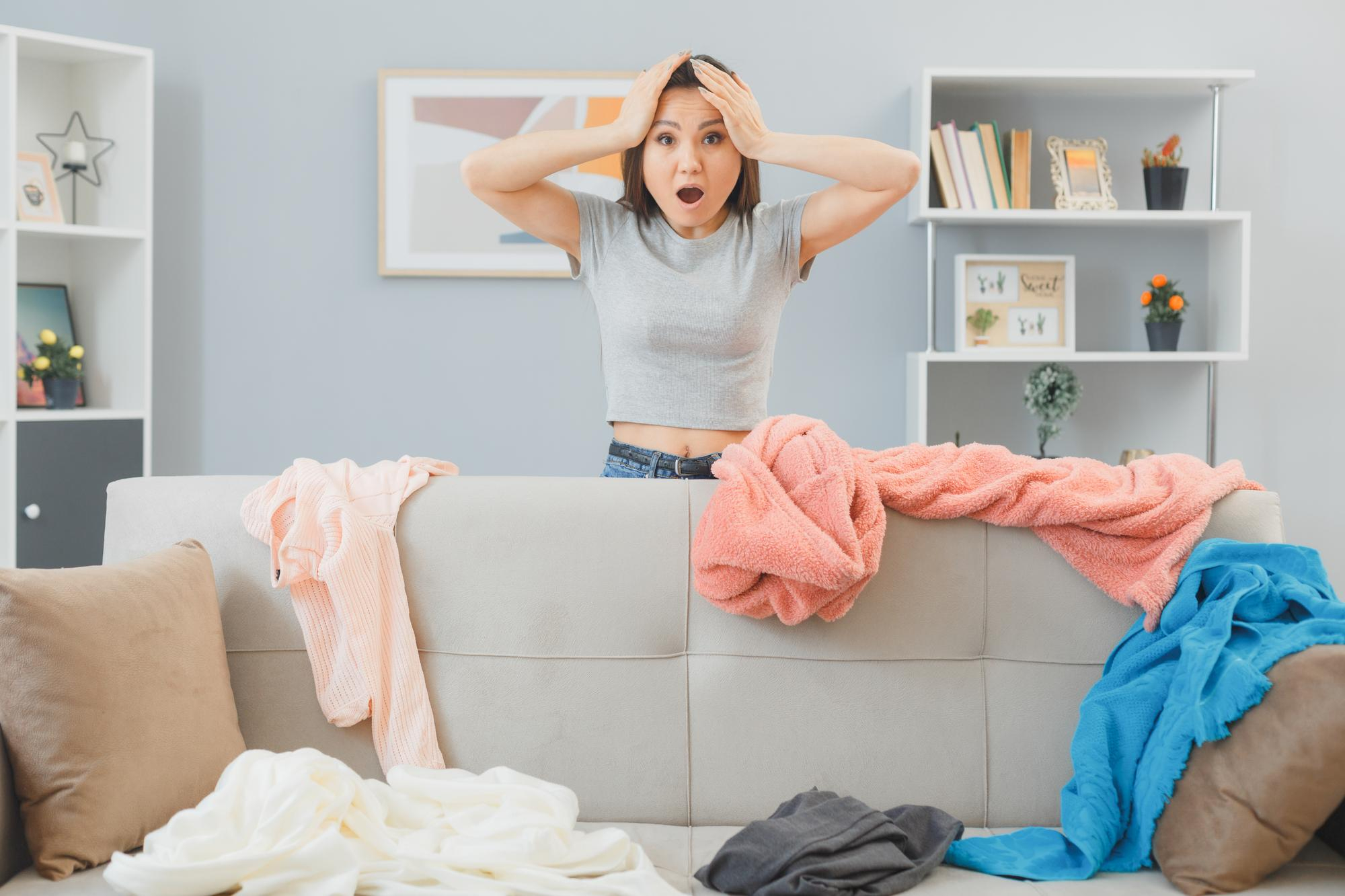 A shocked woman looking at clothes strewn all over in a living room | Source: Freepik