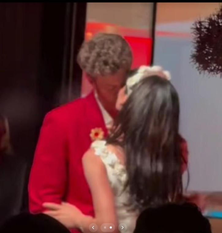 Jack Quaid and Claudia Doumit smile warmly as they move together beneath soft lighting and rich red drapery during their first dance. | Source: TikTok/news.com.au