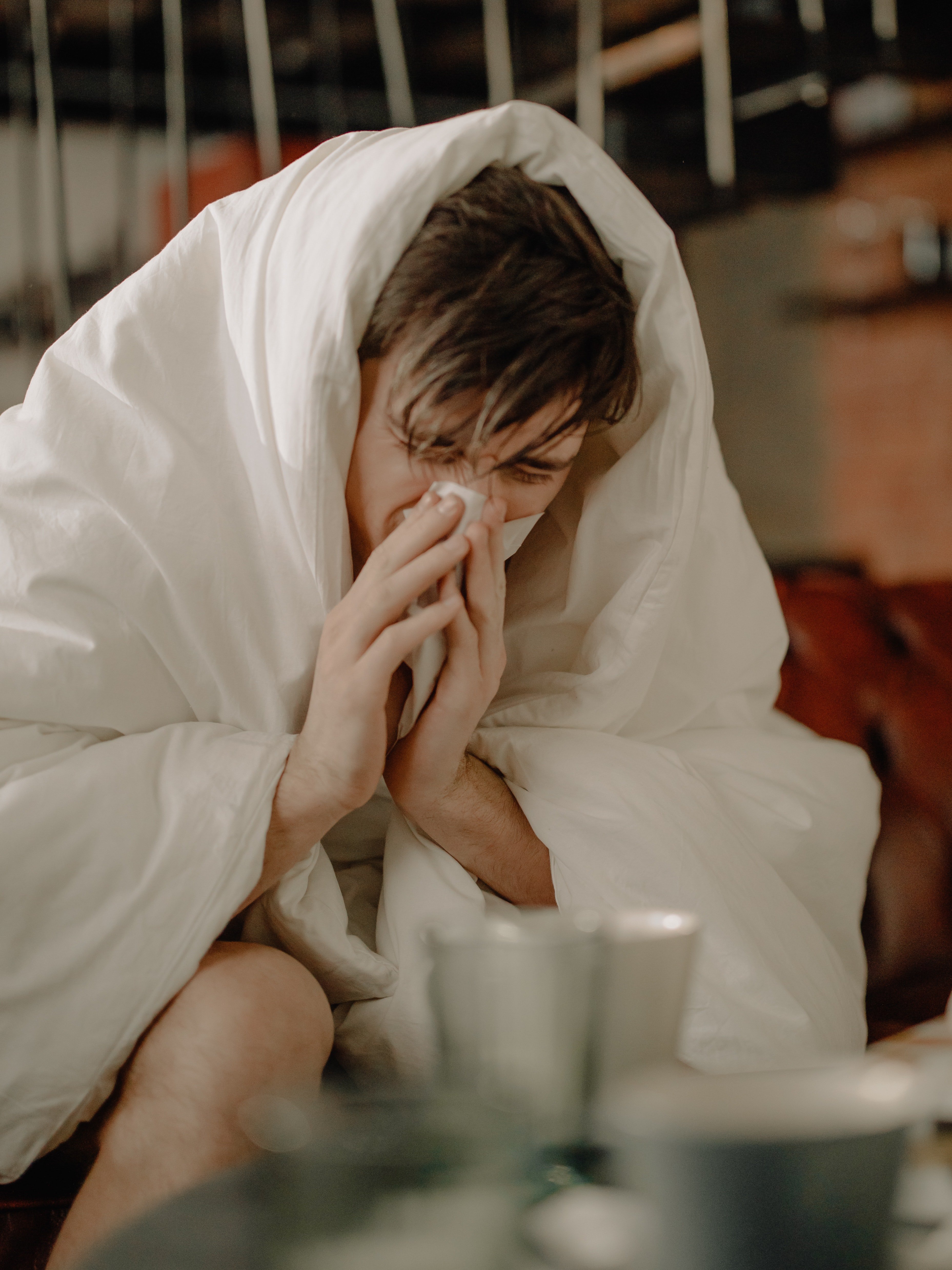 Un joven resfriado cubierto con una manta. | Foto: Pexels