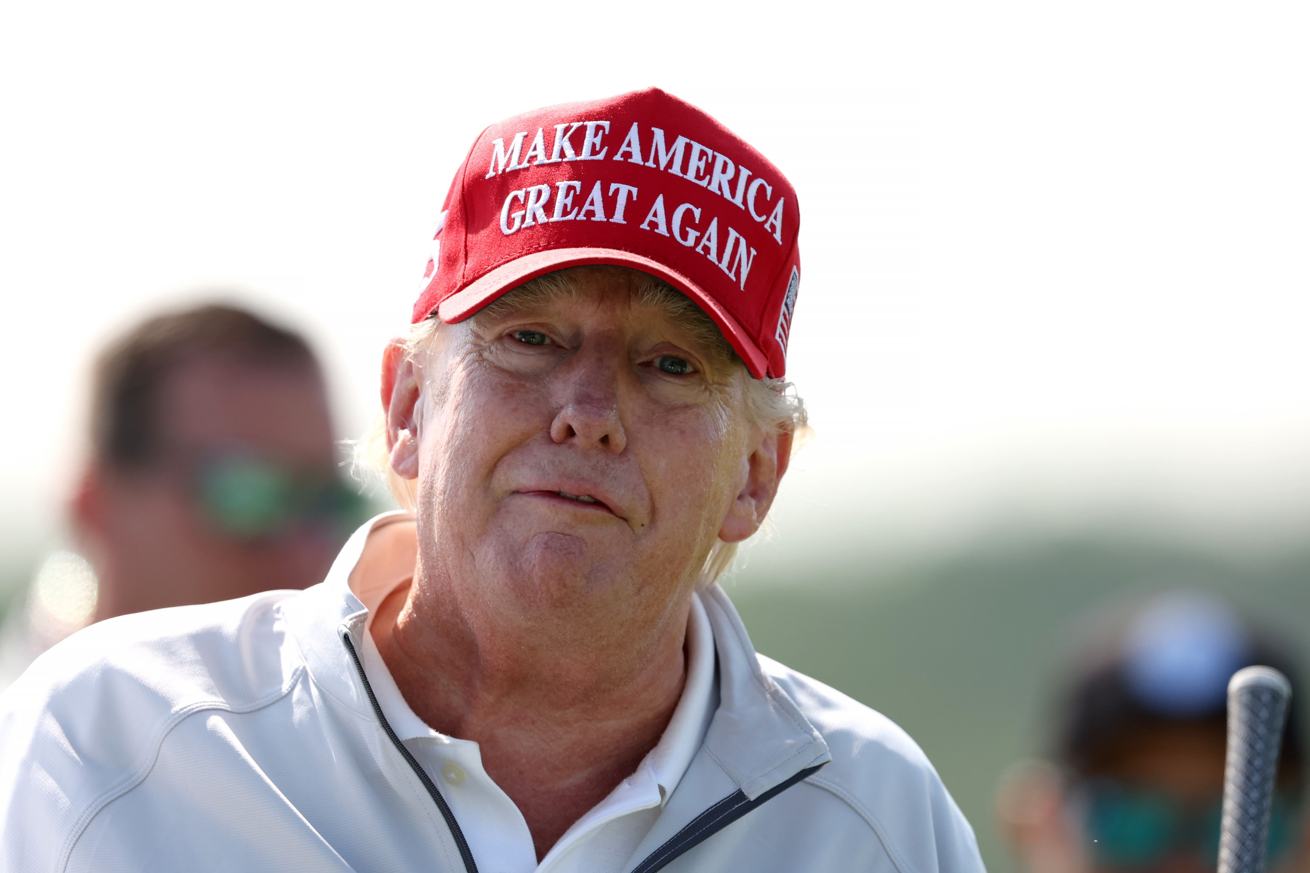 In another shot from the same day, Donald Trump faces the camera with a calm expression. The red tones on his face are especially clear around his cheeks, contrasting with the pale skin near his collar.