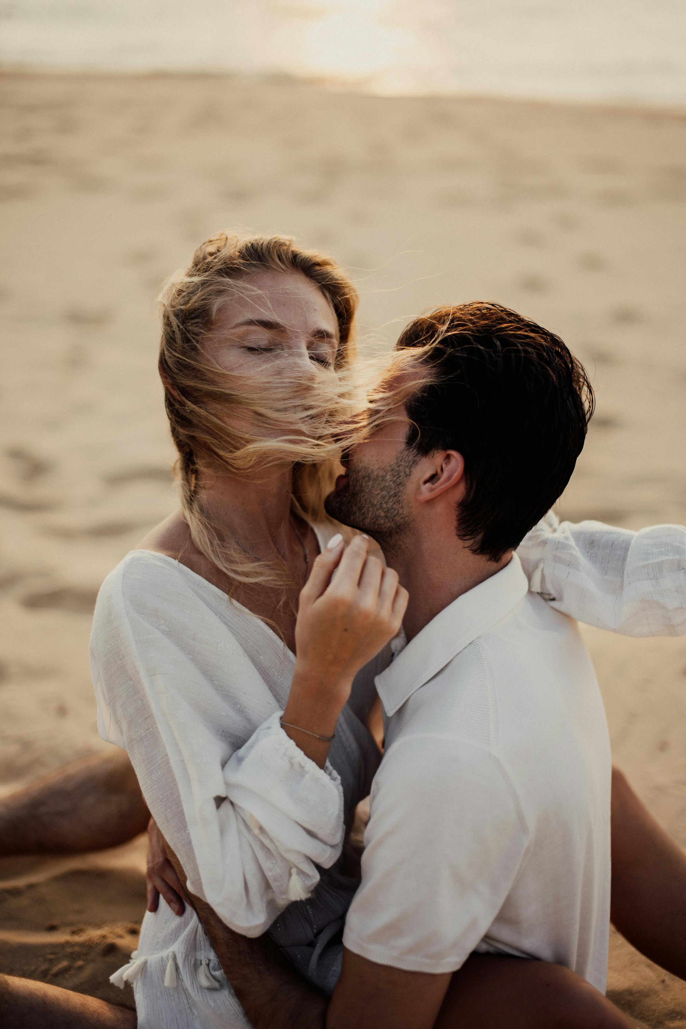 A happy couple sitting on the beach | Source: Pexels