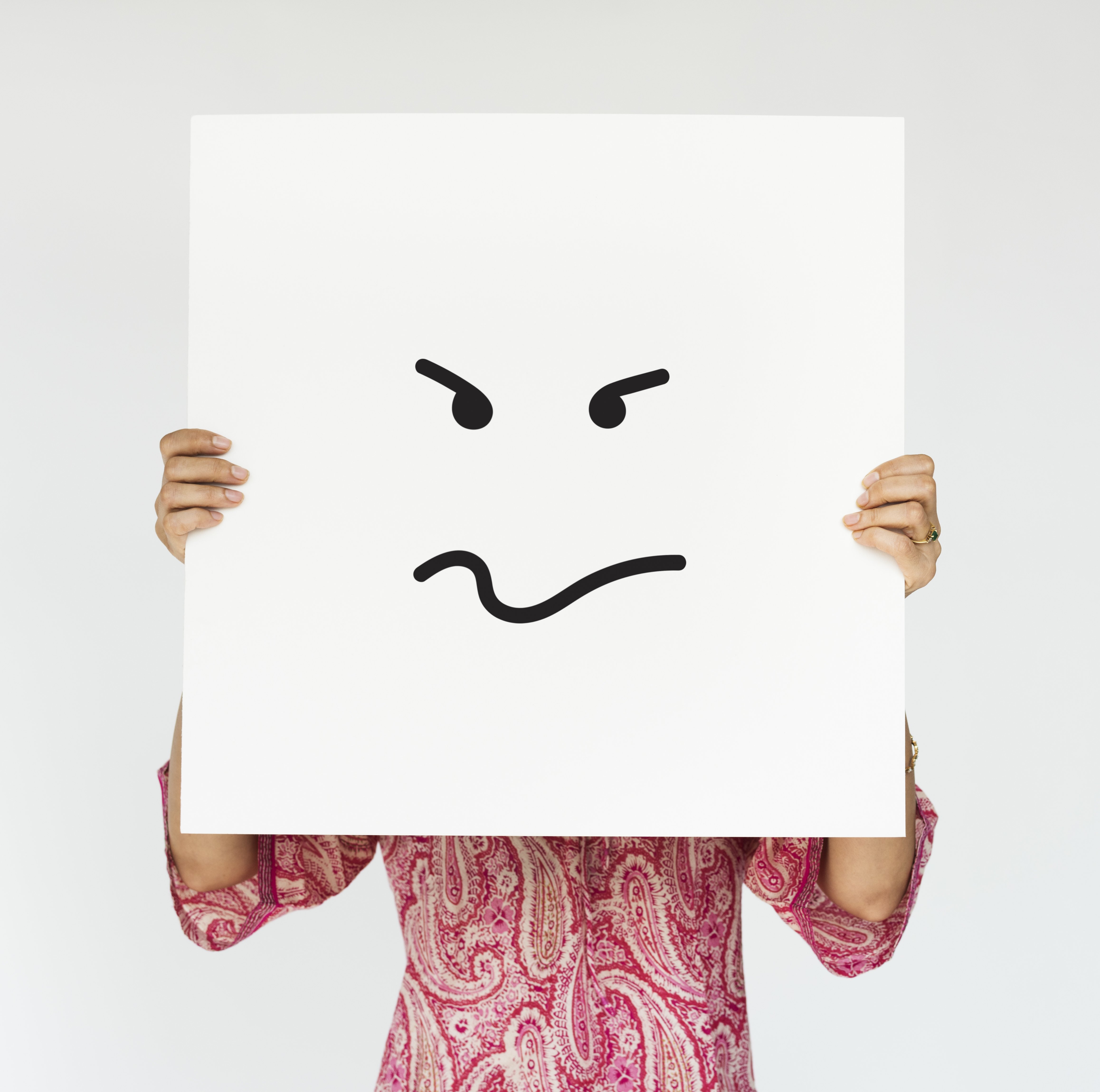 A woman holding an angry face painted on a signboard. | Source: Freepik. 