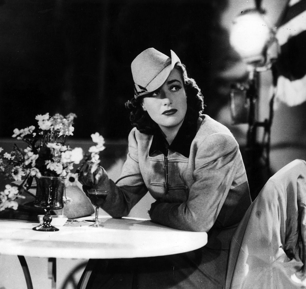 La actriz de cine estadounidense Joan Crawford sentada en una mesa. |Fuente: Getty Images La actriz de cine estadounidense Joan Crawford sentada en una mesa. |Fuente: Getty Images