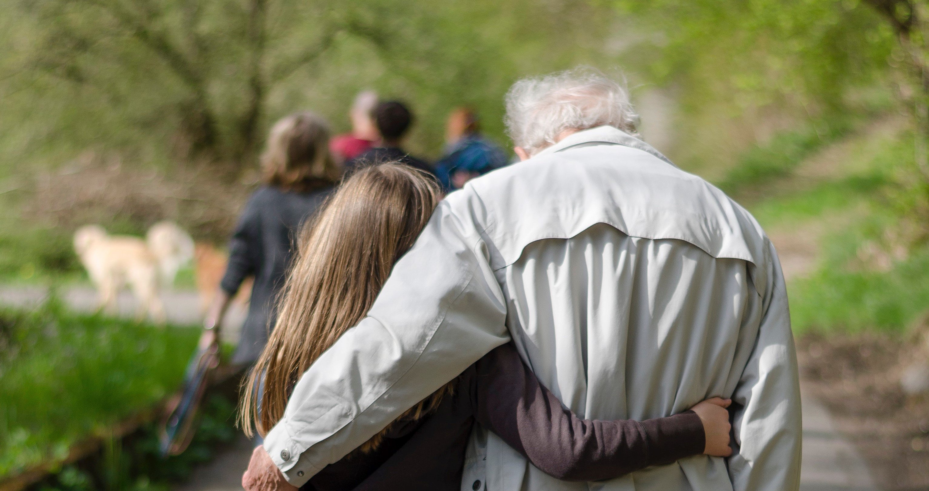 Joven abrazada con anciano mientras caminan | Foto: Unsplash