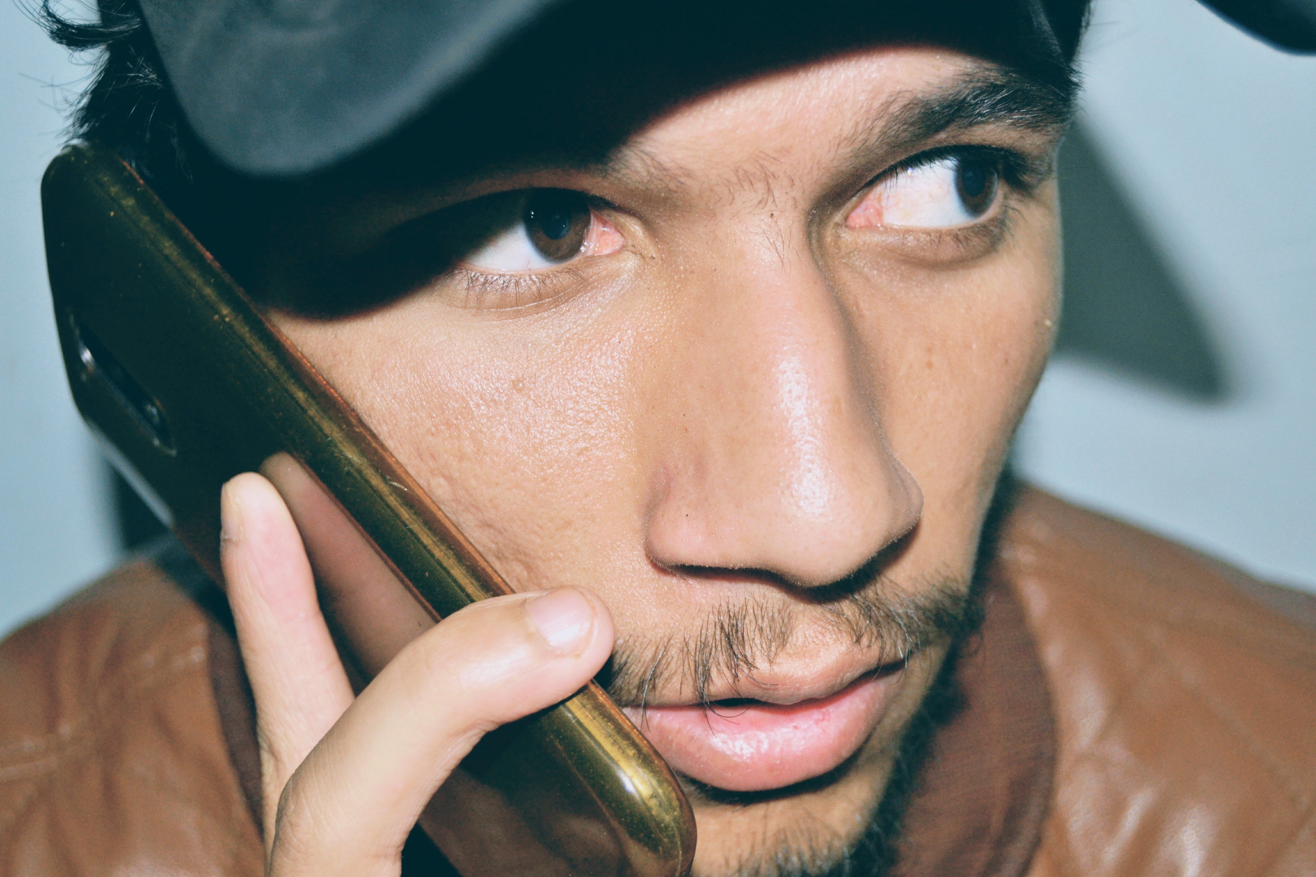 Man in a brown leather jacket talking on phone | Photo: Pexels