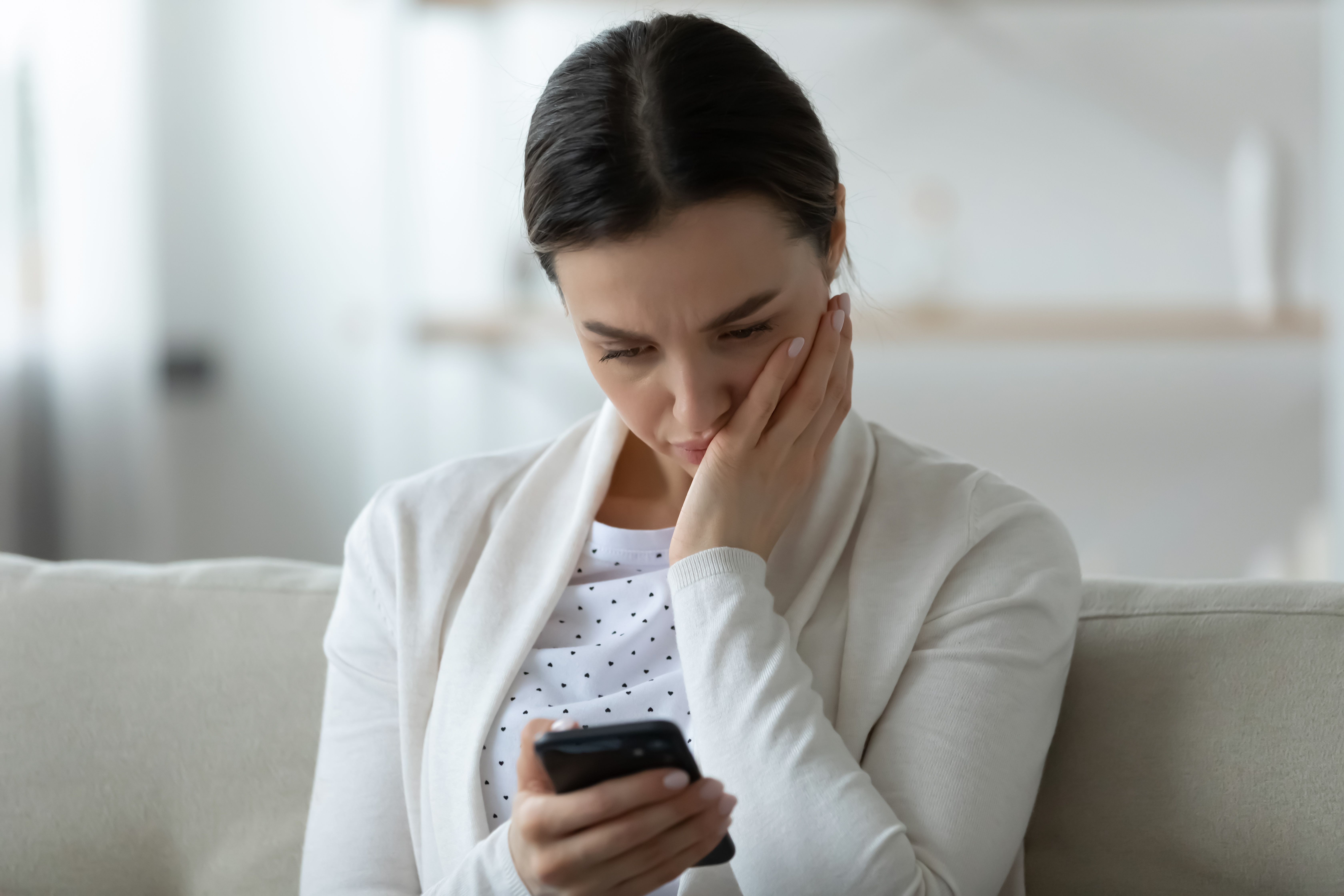 A distraught woman holding and looking at her smartphone | Source: Shutterstock