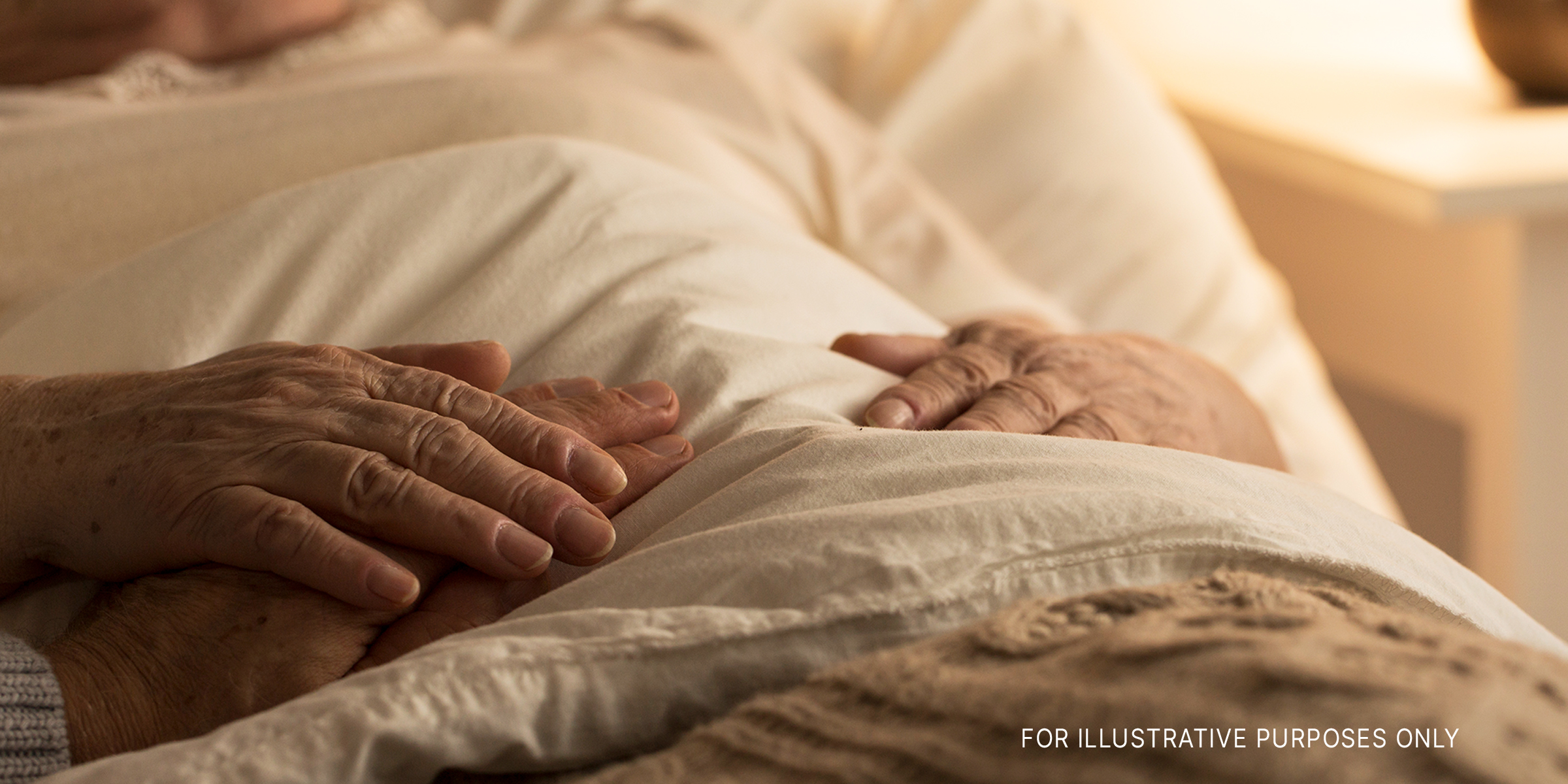 Hands resting on top of the blankets in a hospital bed | Source: Getty Images