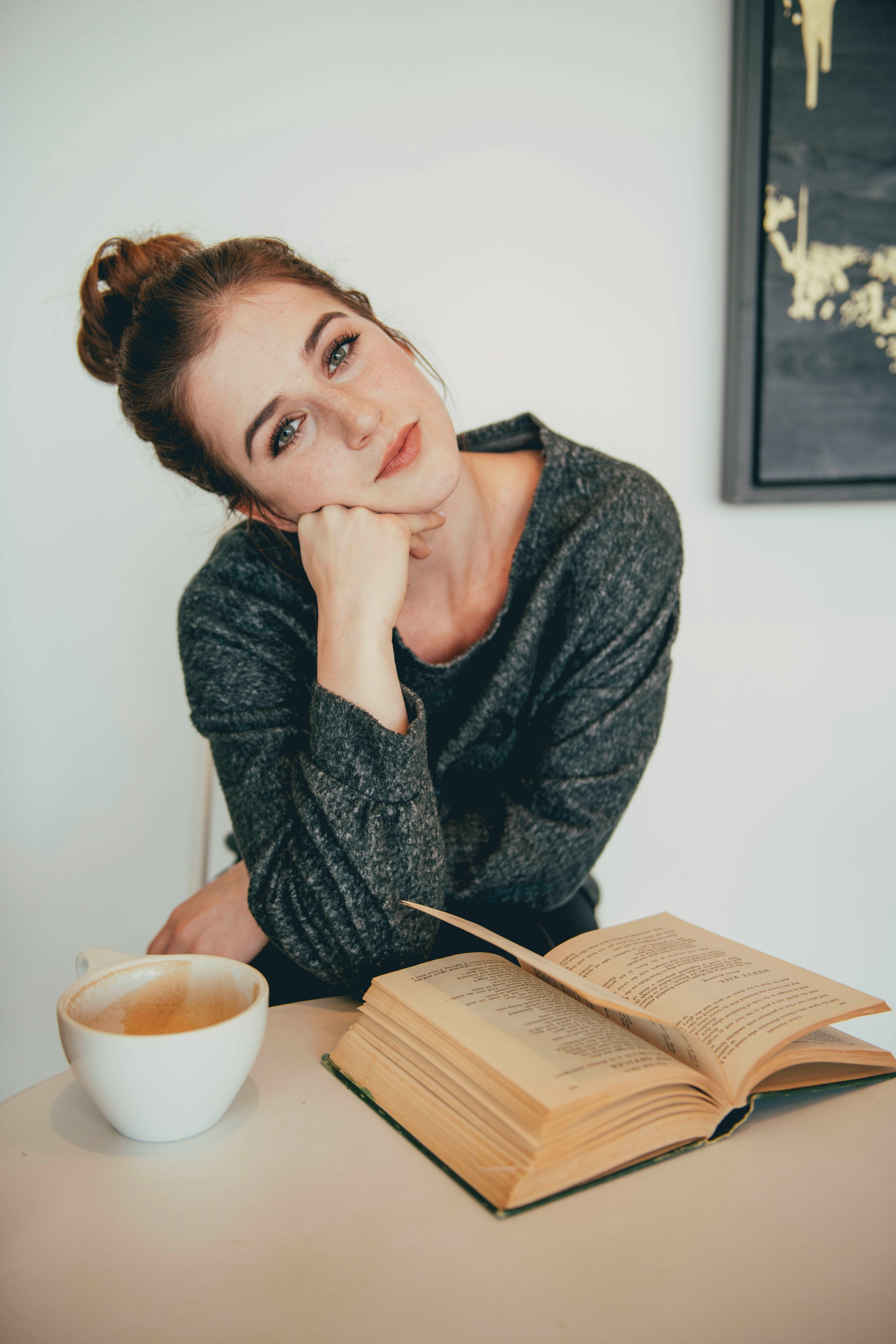 A woman sitting near a cup of coffee and an open book | Source: Unsplash