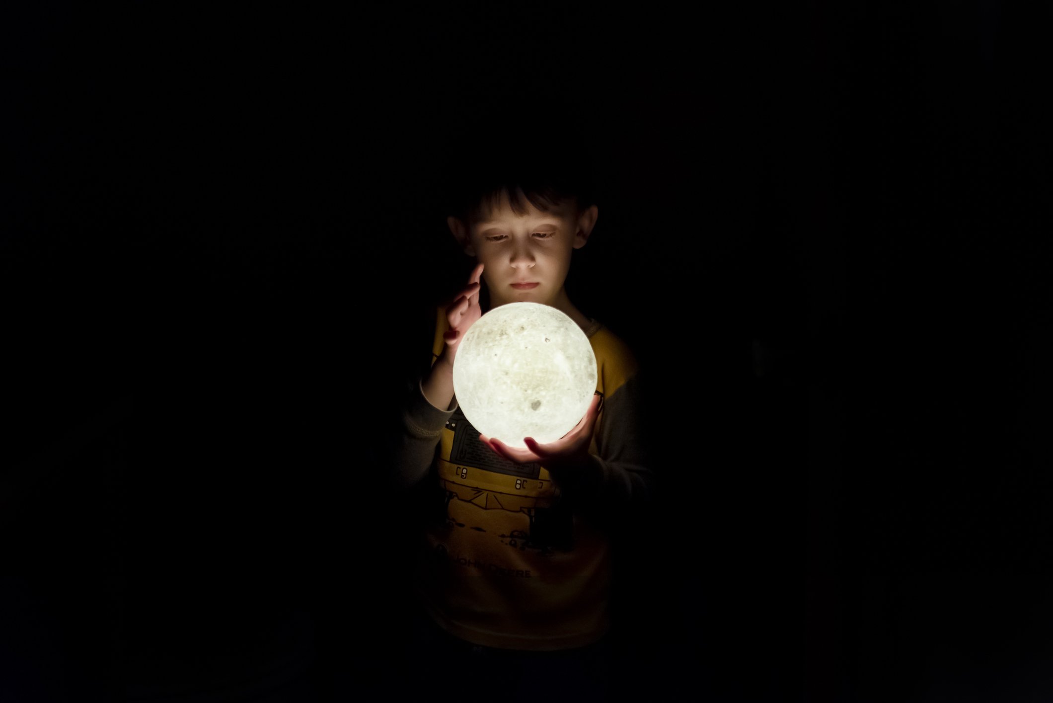 A young boy Looking Into a 3D Moon Lamp. | Photo: Getty Images