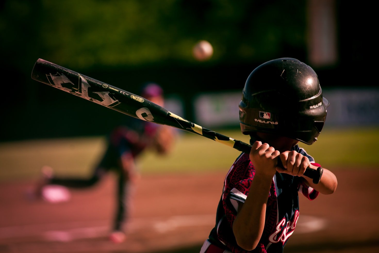 Niño con un bate de béisbol jugando en el campo. | Foto: Unsplash