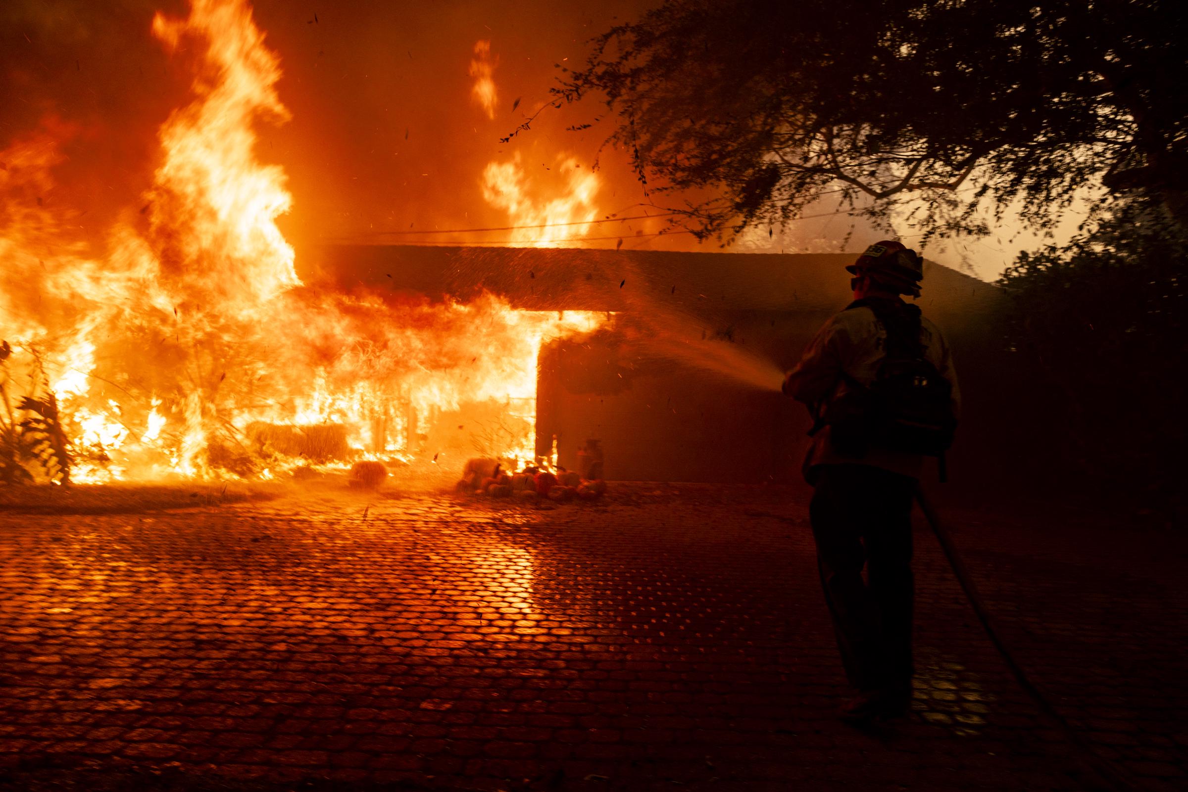 A firefighter dousing a house on fire. | Source: Getty Images