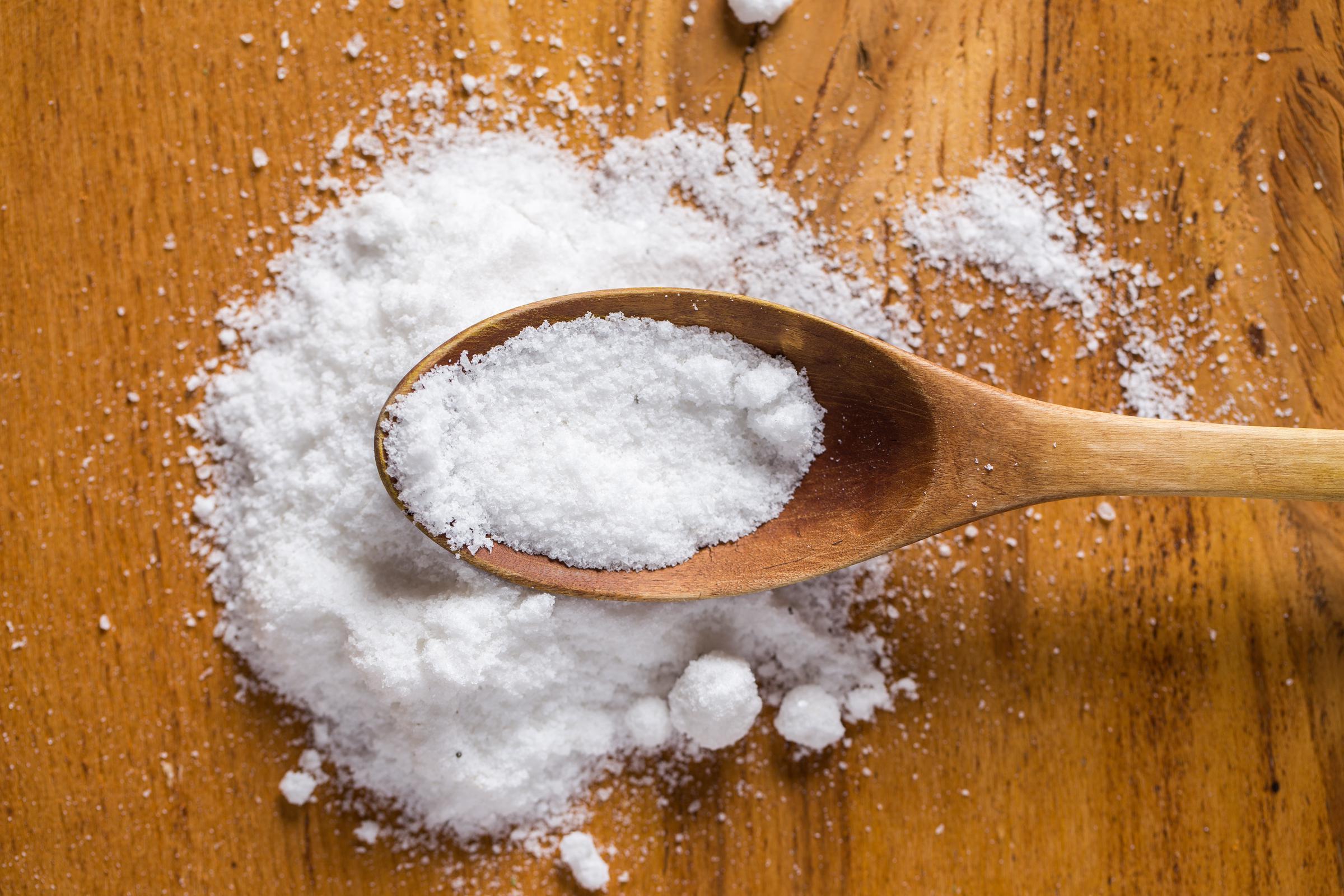 A wooden spoon and heap of salt on a table | Source: Freepik