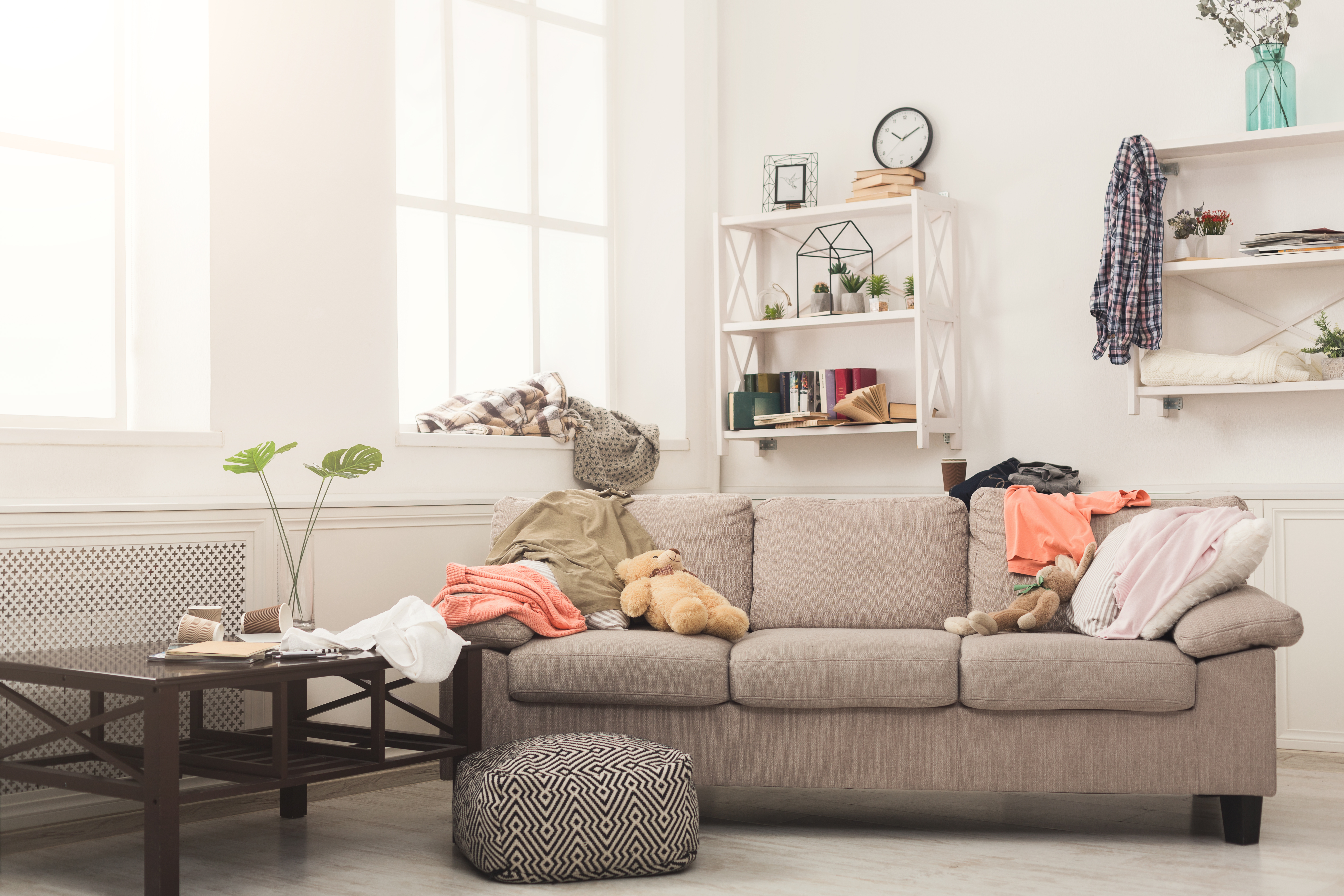 Sofa in messy living room with many stack of clothes. Disorder and mess at home, copy space | Source: Shutterstock