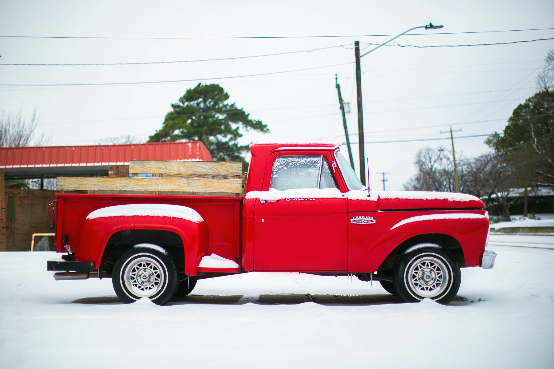 Imagen lateral de una camioneta roja en una carretera nevada. | Foto: Pexels