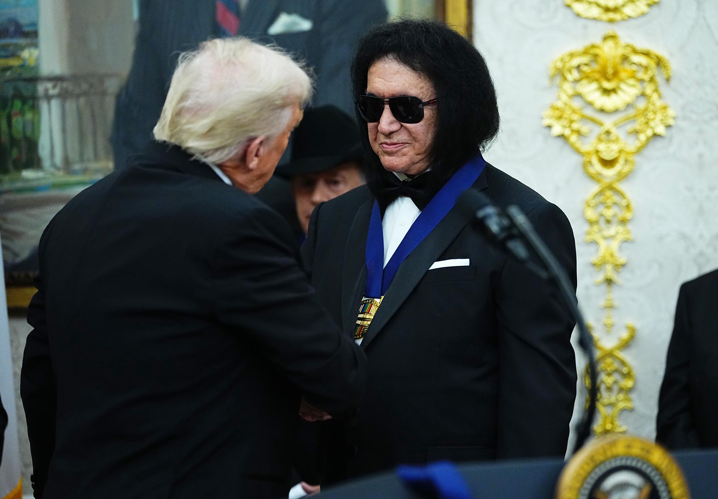Donald Trump presents musician Gene Simmons (R) of the rock band KISS a medal for the Kennedy Center Honorees during a medal presentation in the Oval Office on December 6, 2025 in Washington, DC  | Source: Getty Images