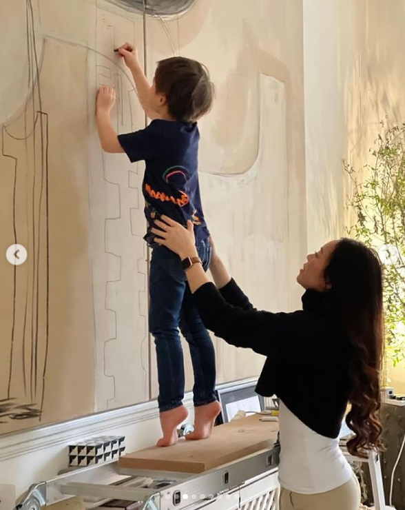 Christopher Woolf Mapelli Mozzi shows off his artistic skills, drawing on a portrait while his mom, Dara Huang, holds him from behind. | Source: Instagram/dara_huang