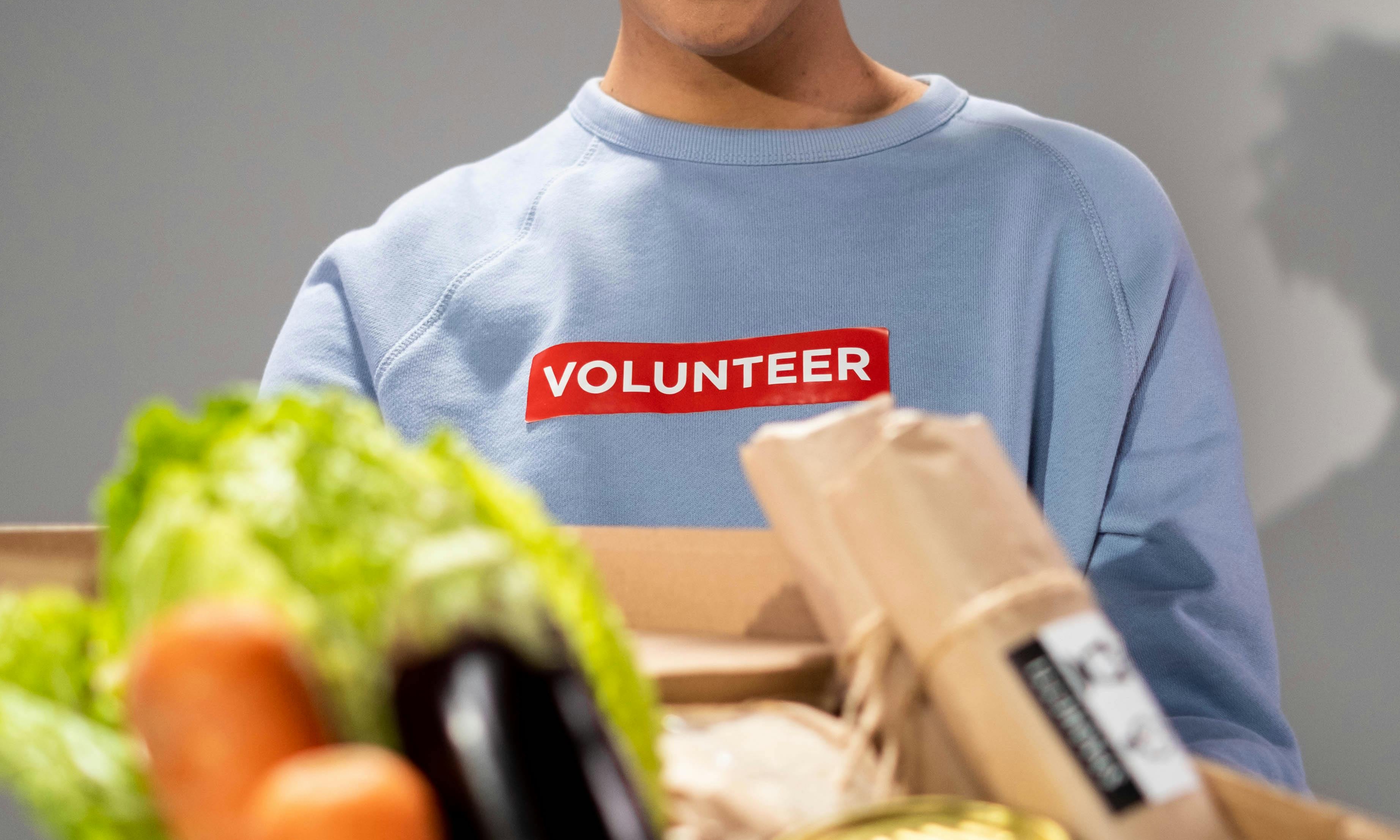 A woman with a "volunteer"-printed T-shirt holding a food parcel | Source: Pexels