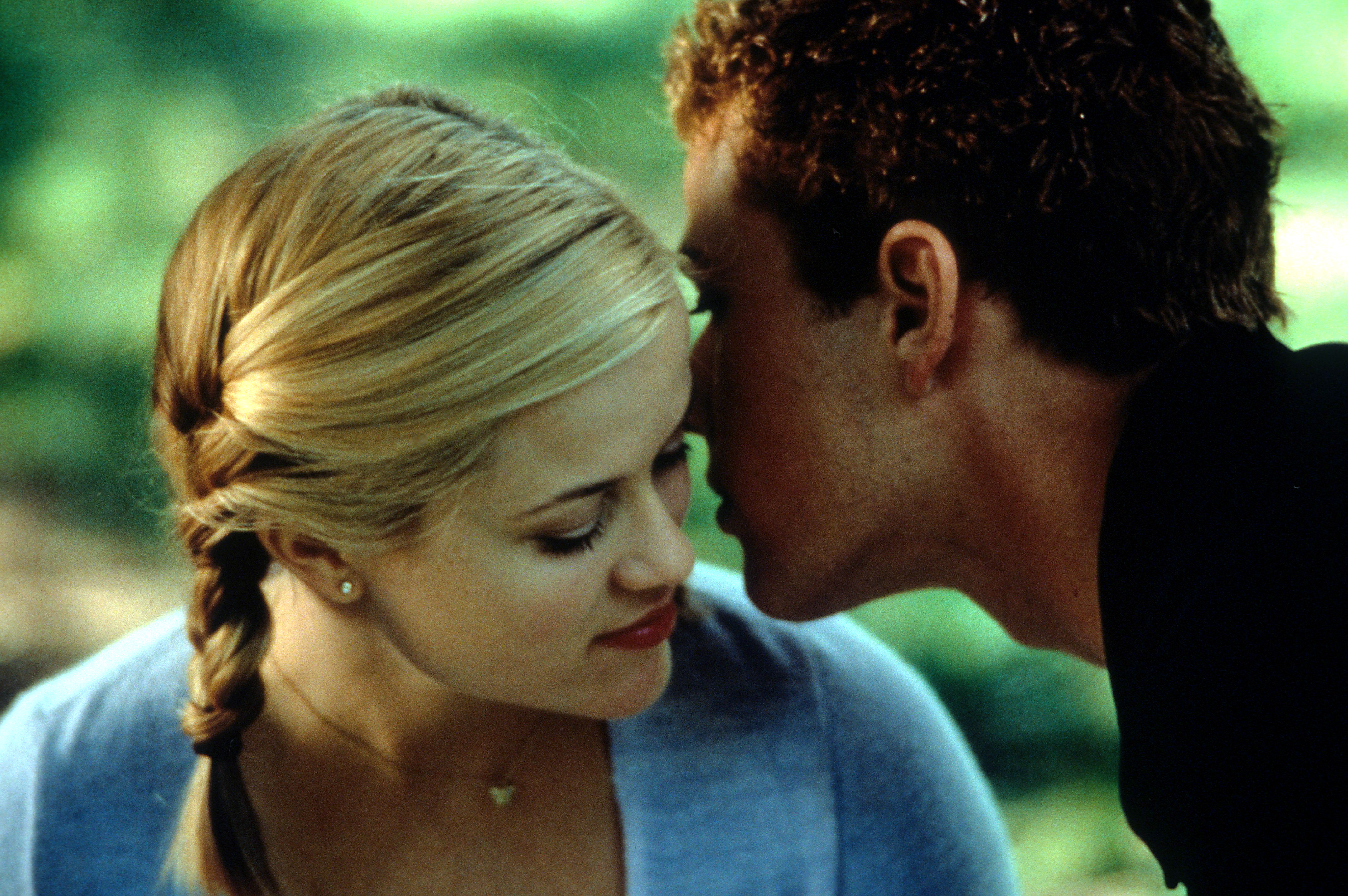 Reese Witherspoon listens as Ryan Phillippe whispers in her ear in a scene from the film "Cruel Intentions" in 1999. | Source: Getty Images