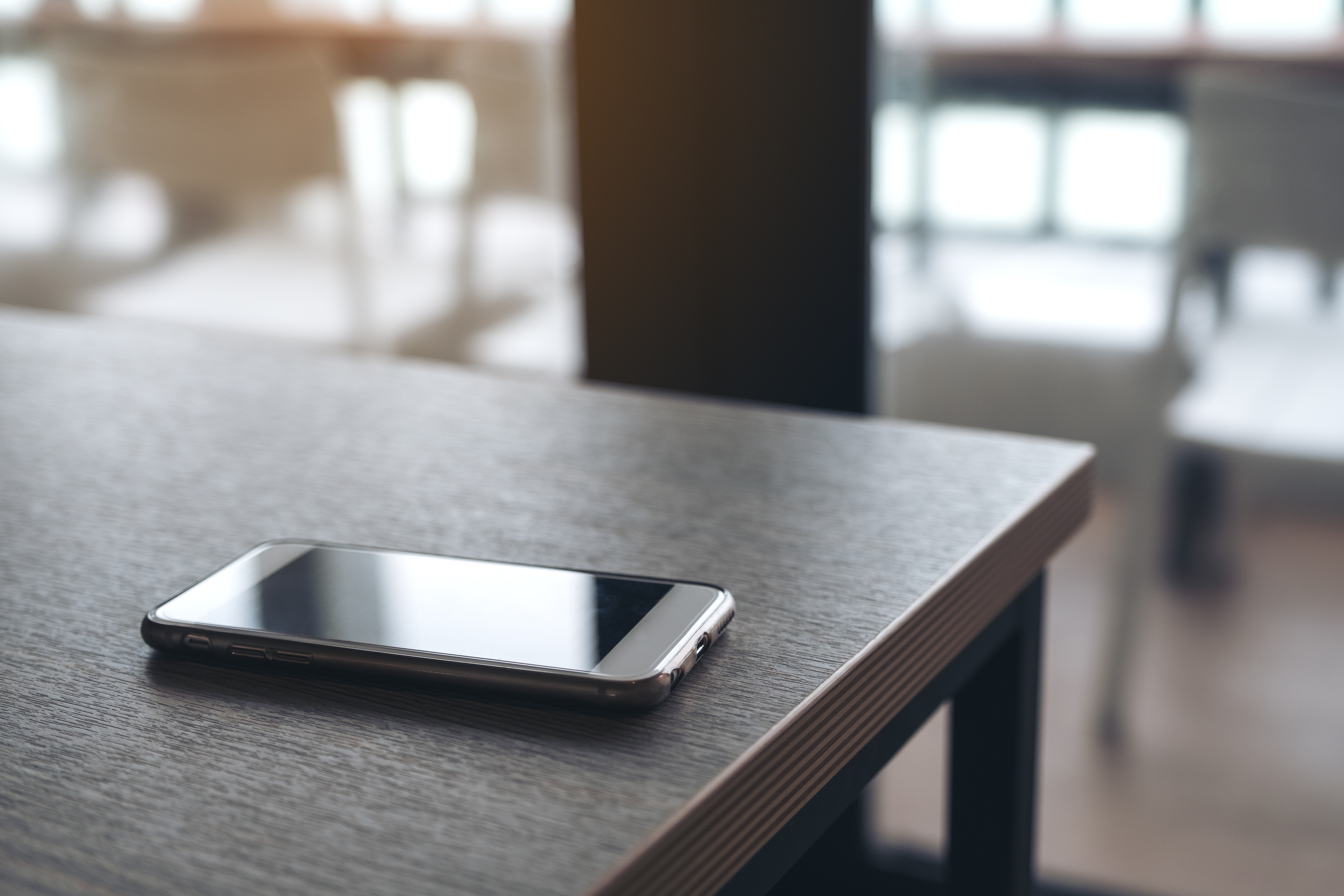 A single mobile phone on wooden table. | Source: Shutterstock