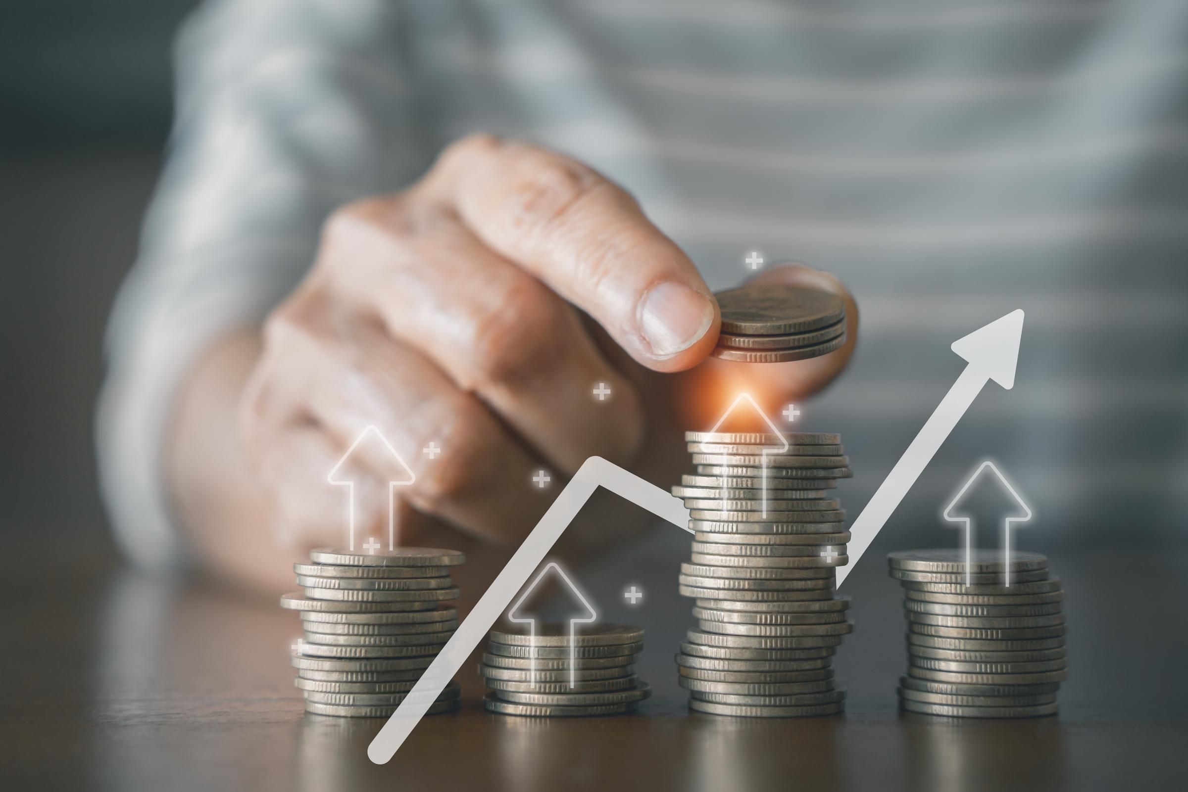 A person adding more coins on stack of coins | Source: Shutterstock