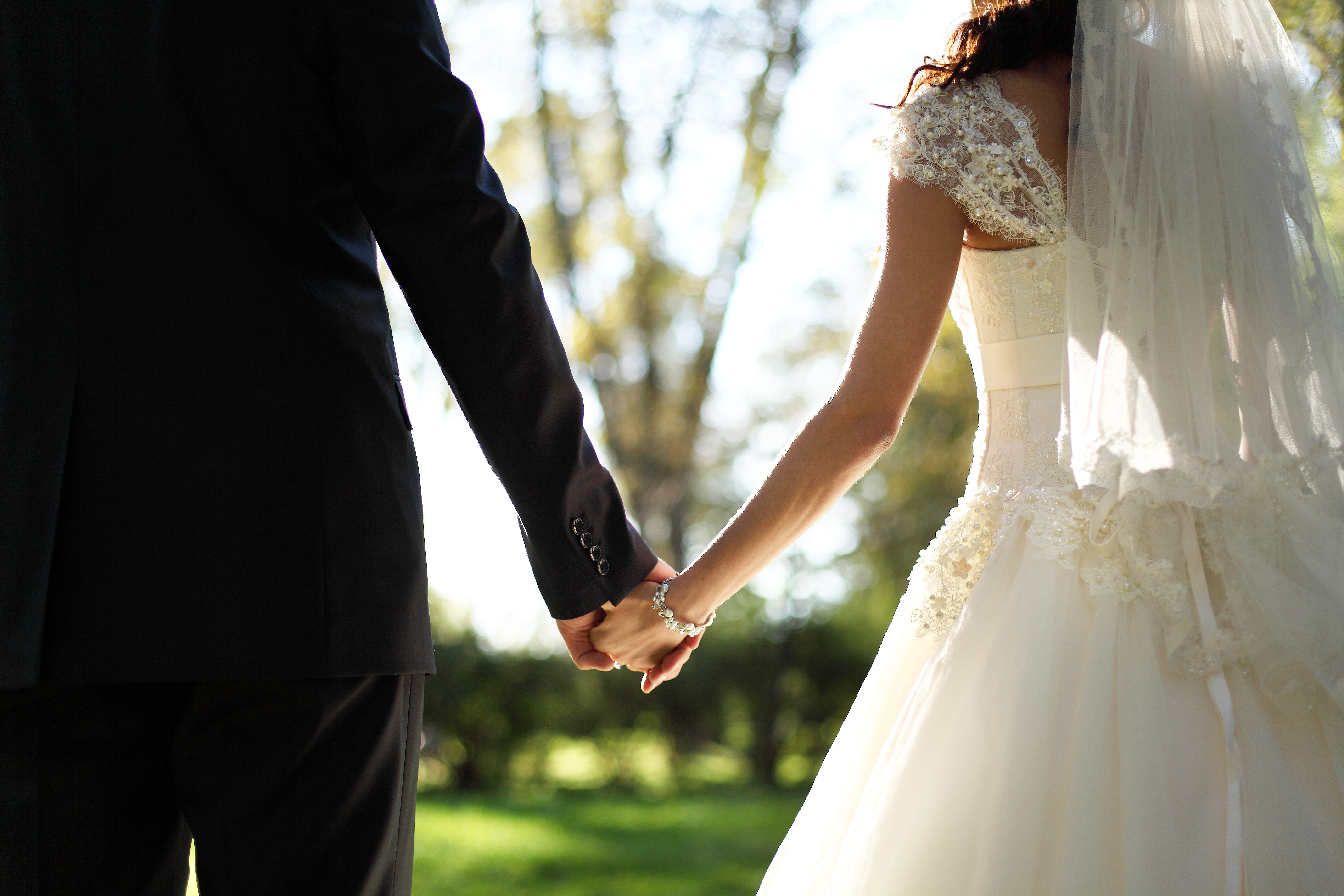 Braut und Bräutigam halten sich an ihrem großen Tag an den Hände. | Quelle: Shutterstock