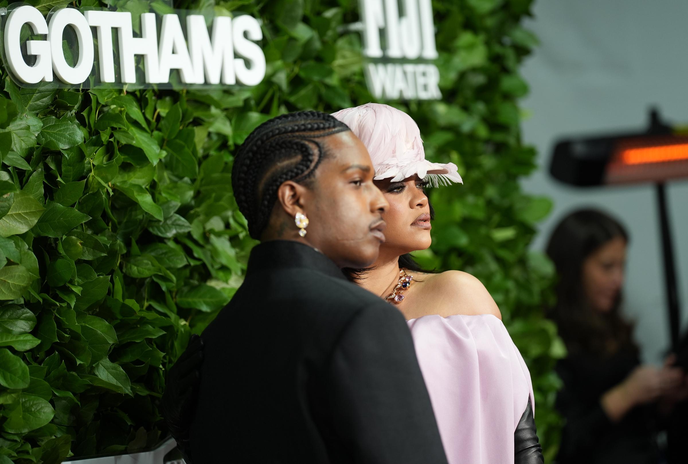 A$AP Rocky and Rihanna stand in perfect profile, facing forward with serious expressions. Their poised, statuesque presence captures a quiet, fashion-forward intensity on the red carpet.