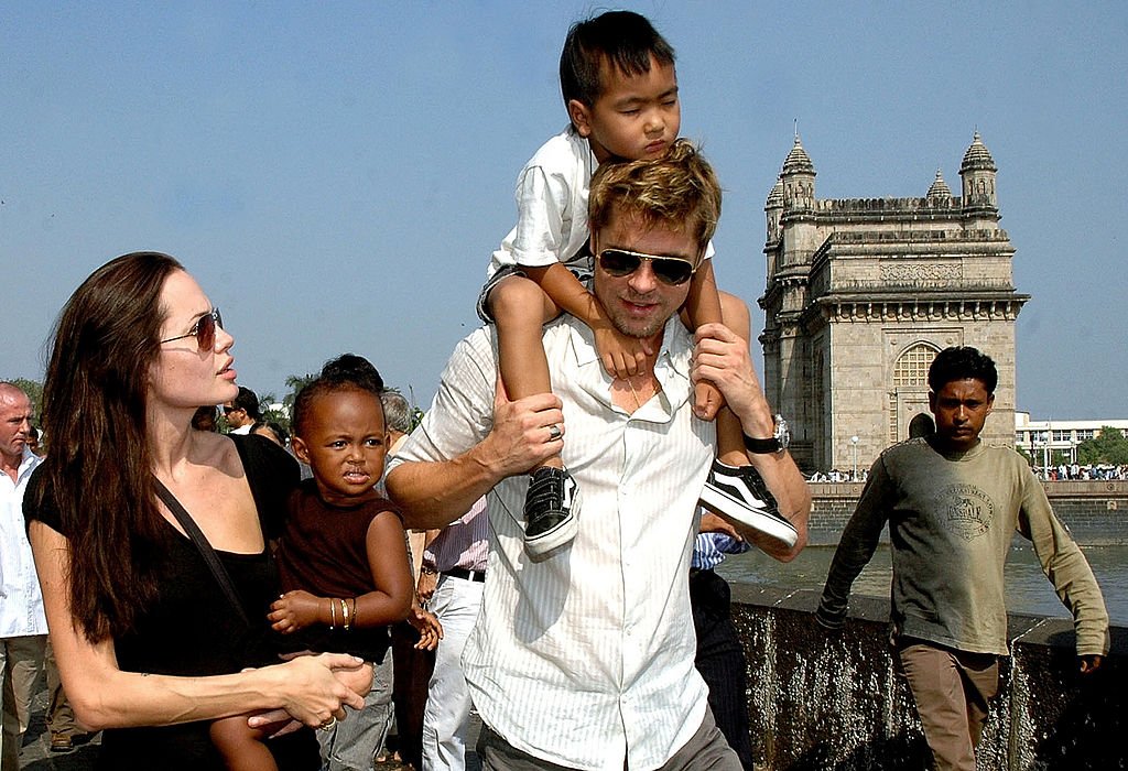 US actor Angelina Jolie (L) holds daughter Zahara as husband and actor Brad Pitt (C) carries son Maddox during a stroll on the seafront promenade at the historic Gateway of India, (R) outside their hotel in Mumbai, 12 November 2006.  | Photo: Getty Images