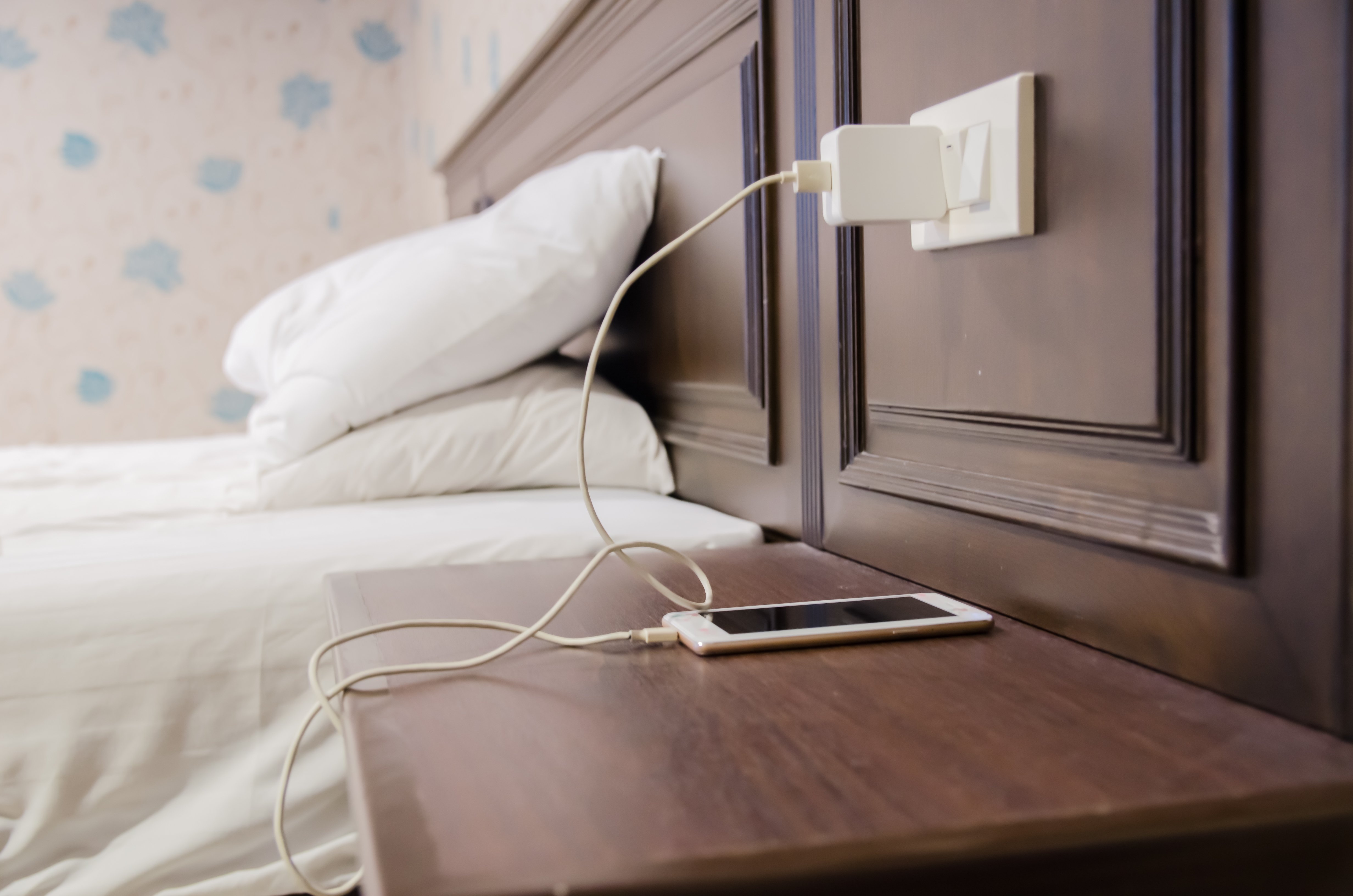 Adapter zum Aufladen von Smartphones auf dem Tisch neben dem Bett im Hotel | Quelle: Shutterstock