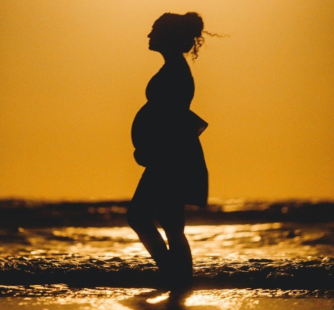 Perfil de una embarazada caminando durante el atardecer. | Foto: Unsplash