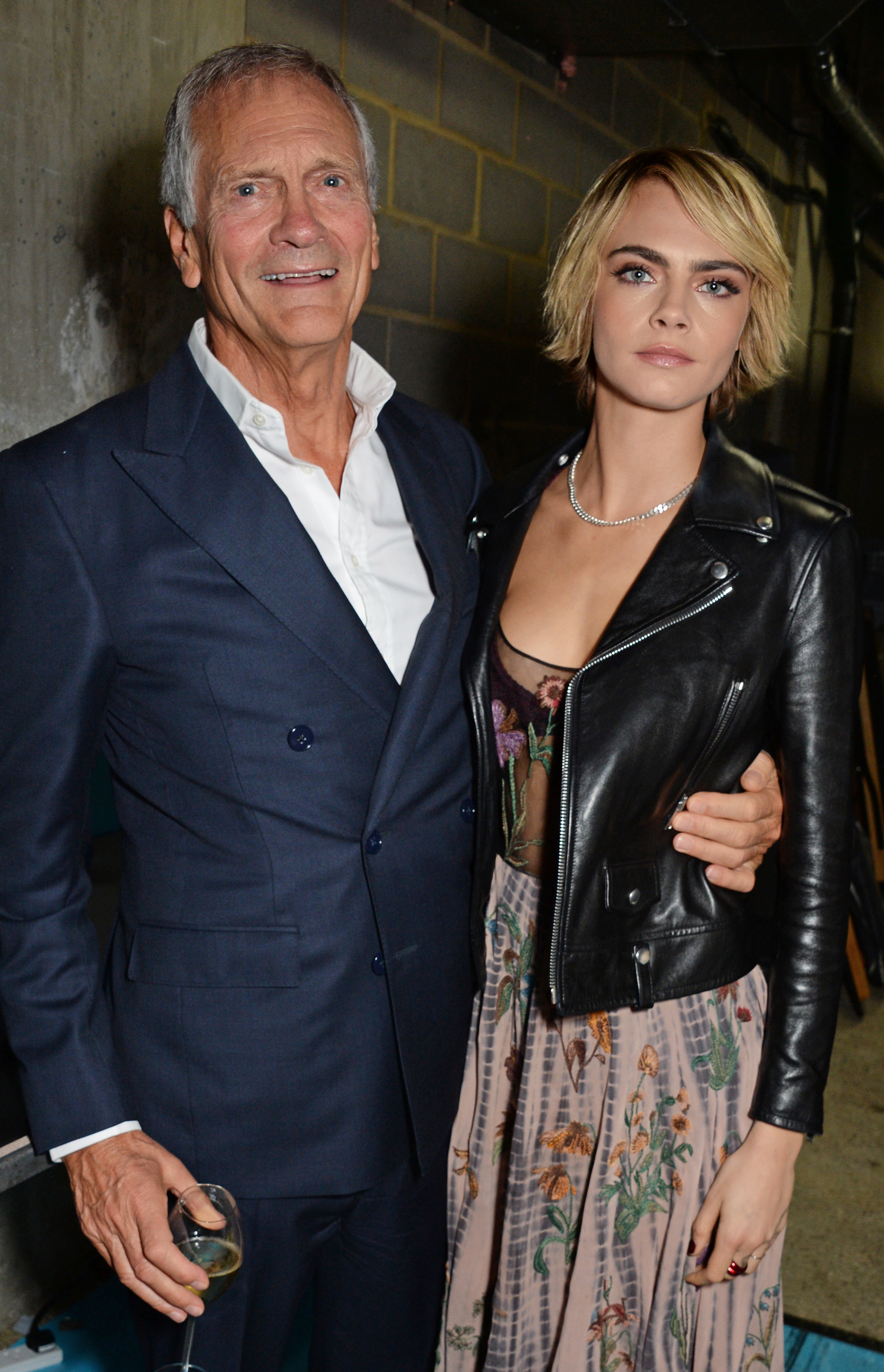 Charles Delevingne and Cara Delevigne pose at the TAG Heuer auction featuring unseen art work from the "Don't Crack Under Pressure" Campaign in association with Cara Delevingne and David Yarrow at Maddox Gallery on October 22, 2018, in London, England | Source: Getty Images