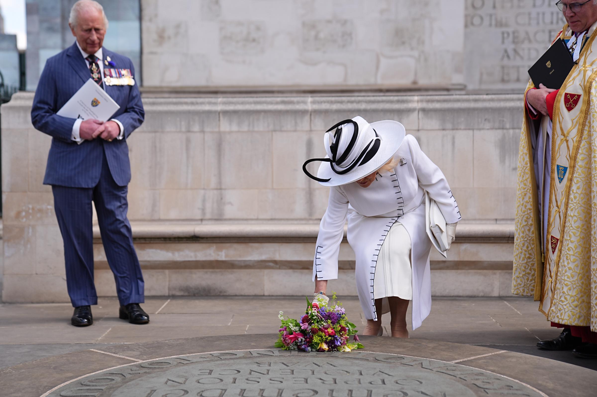 King Charles III and Dean of Westminster, the Very Reverend Dr David Hoyle look on as Queen Camilla lays flowers at the Innocent Victims' Memorial at Westminster Abbey in London in London, England, on May 8, 2025 | Source: Getty Images