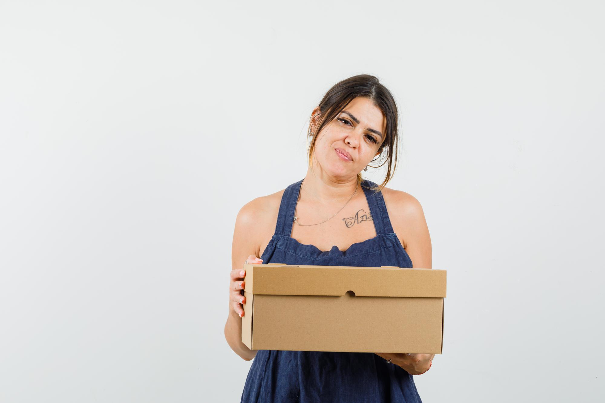 A young woman looking unimpressed while holding a package | Source: Freepik