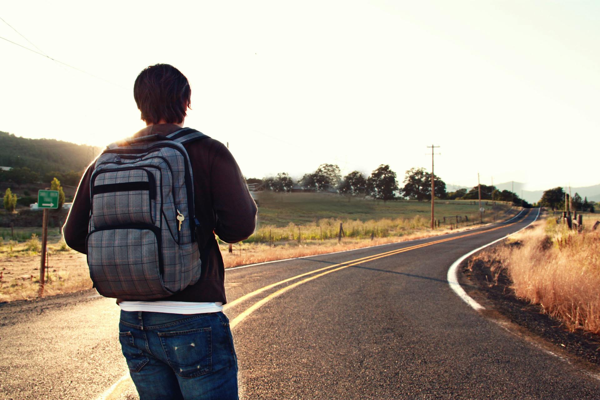 A man with a backpack standing on a road | Source: Pexels