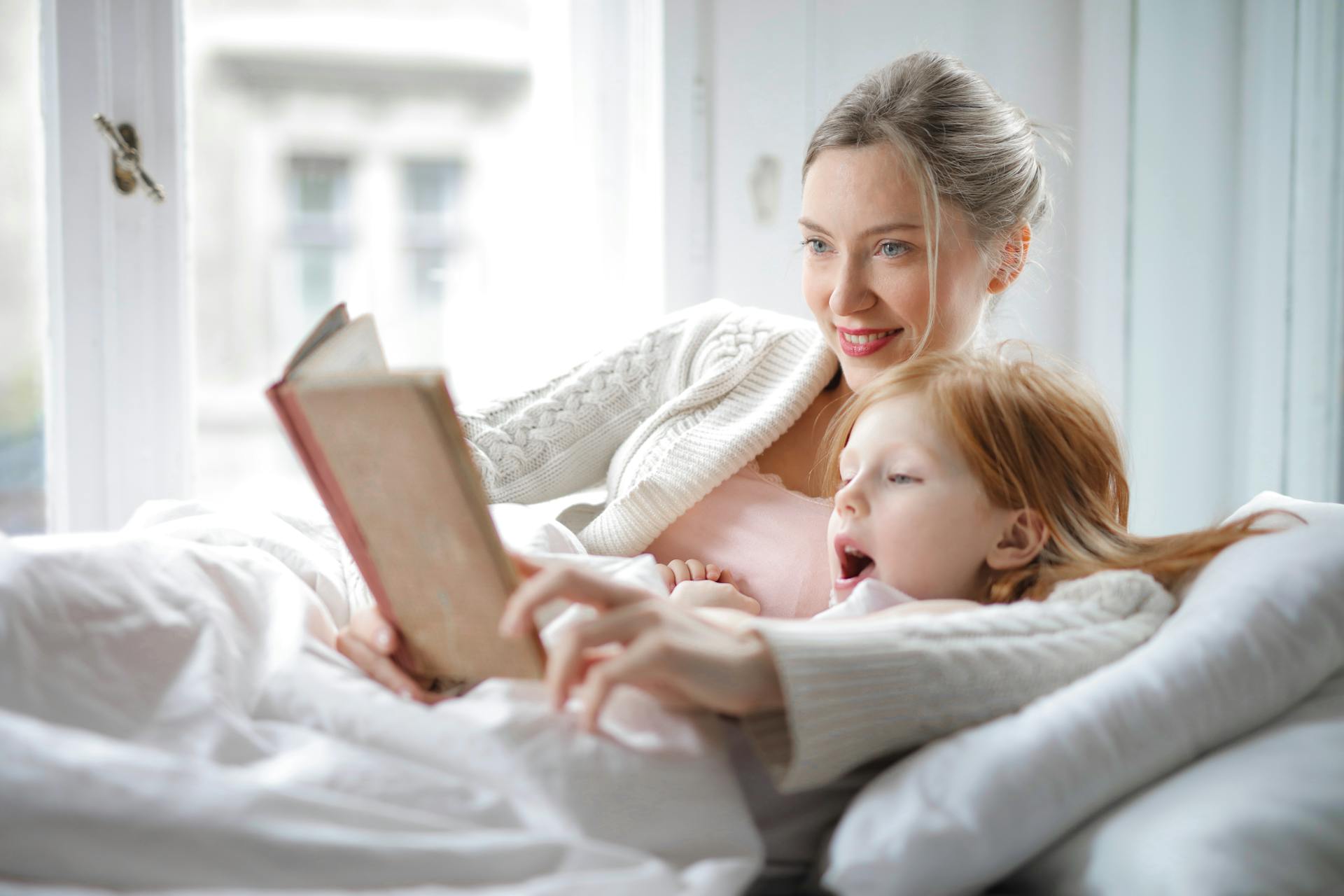 A woman reading to her daughter | Source: Pexels