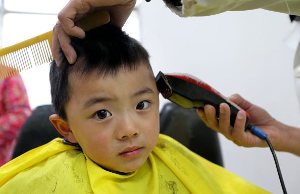 A boy gets a haircut at the saloon | Photo: Getty Images