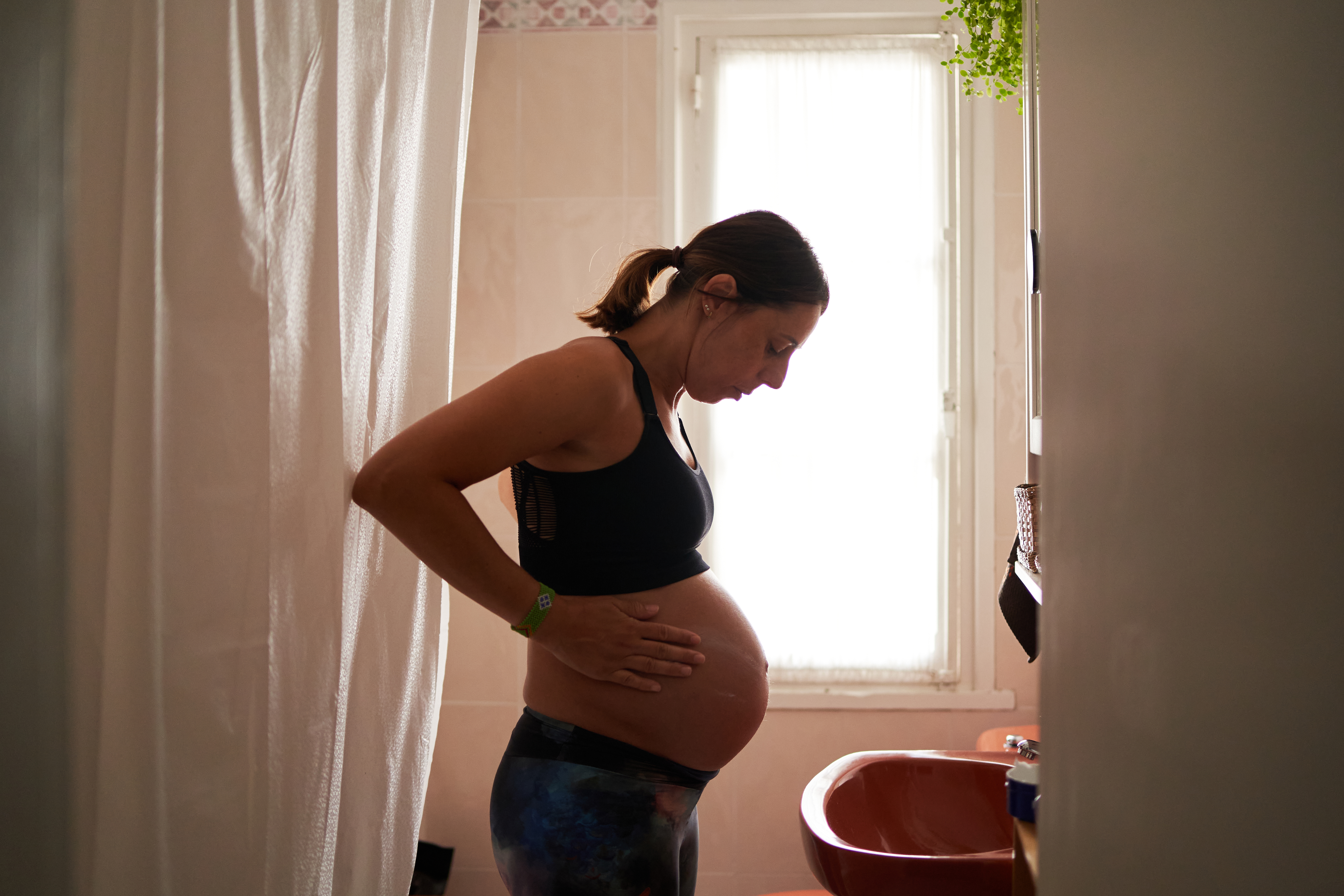Side view of a pregnant woman moisturizing her belly | Source: Getty Images