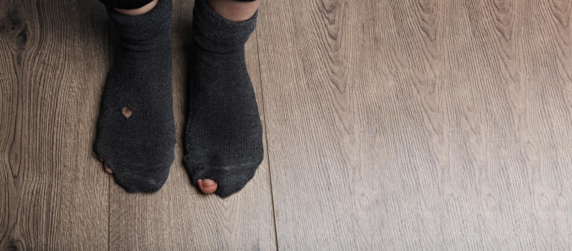 A pair of feet wearing worn-out socks | Source: Shutterstock