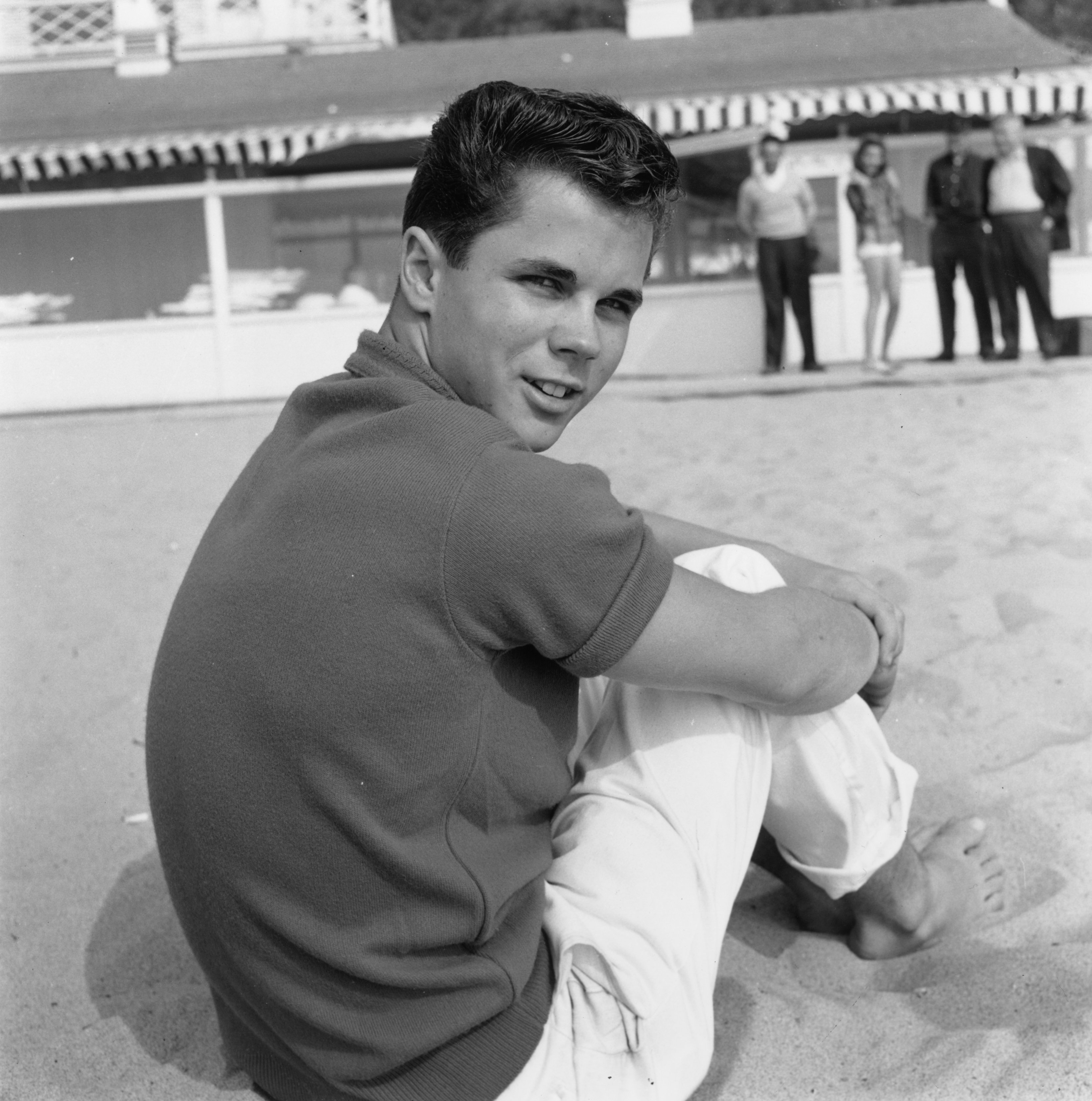 American actor Tony Dow looks over his shoulder while sitting on a beach, Santa Monica, California. | Source: Getty Images