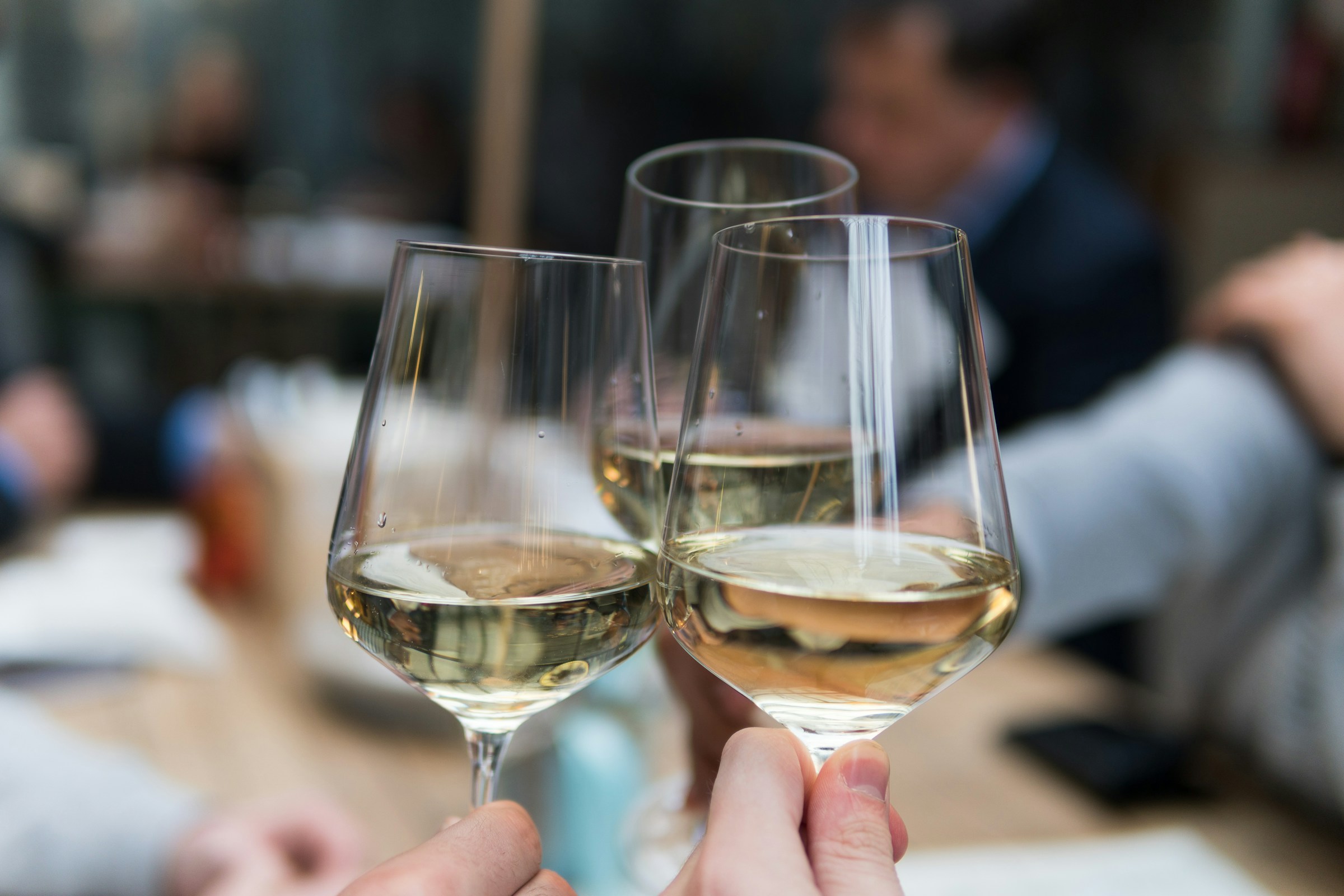 A closeup of three people raising their glasses of drink in a toast | Source: Unsplash