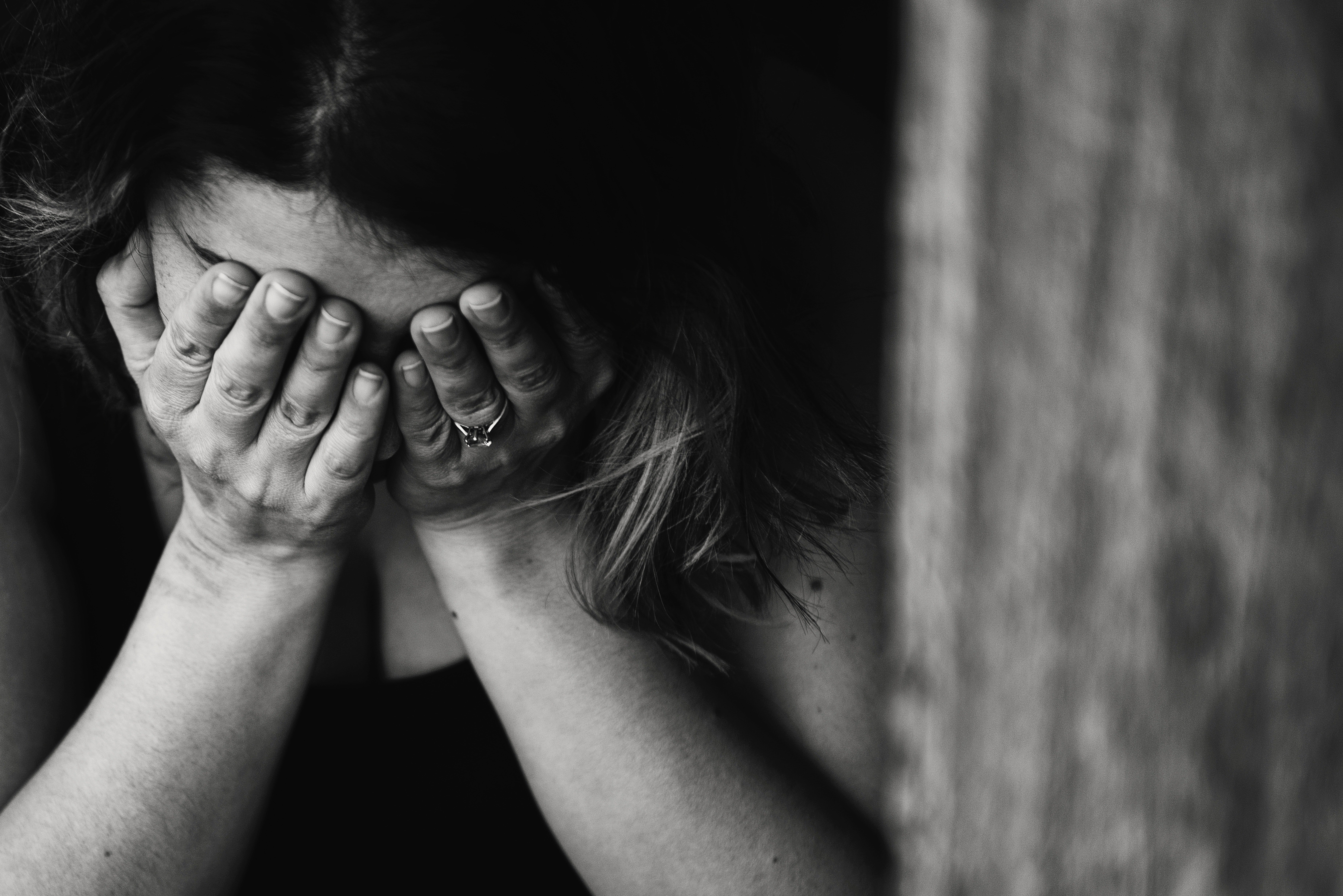Una mujer joven llora con su rostro entre sus manos. | Foto: Pexels