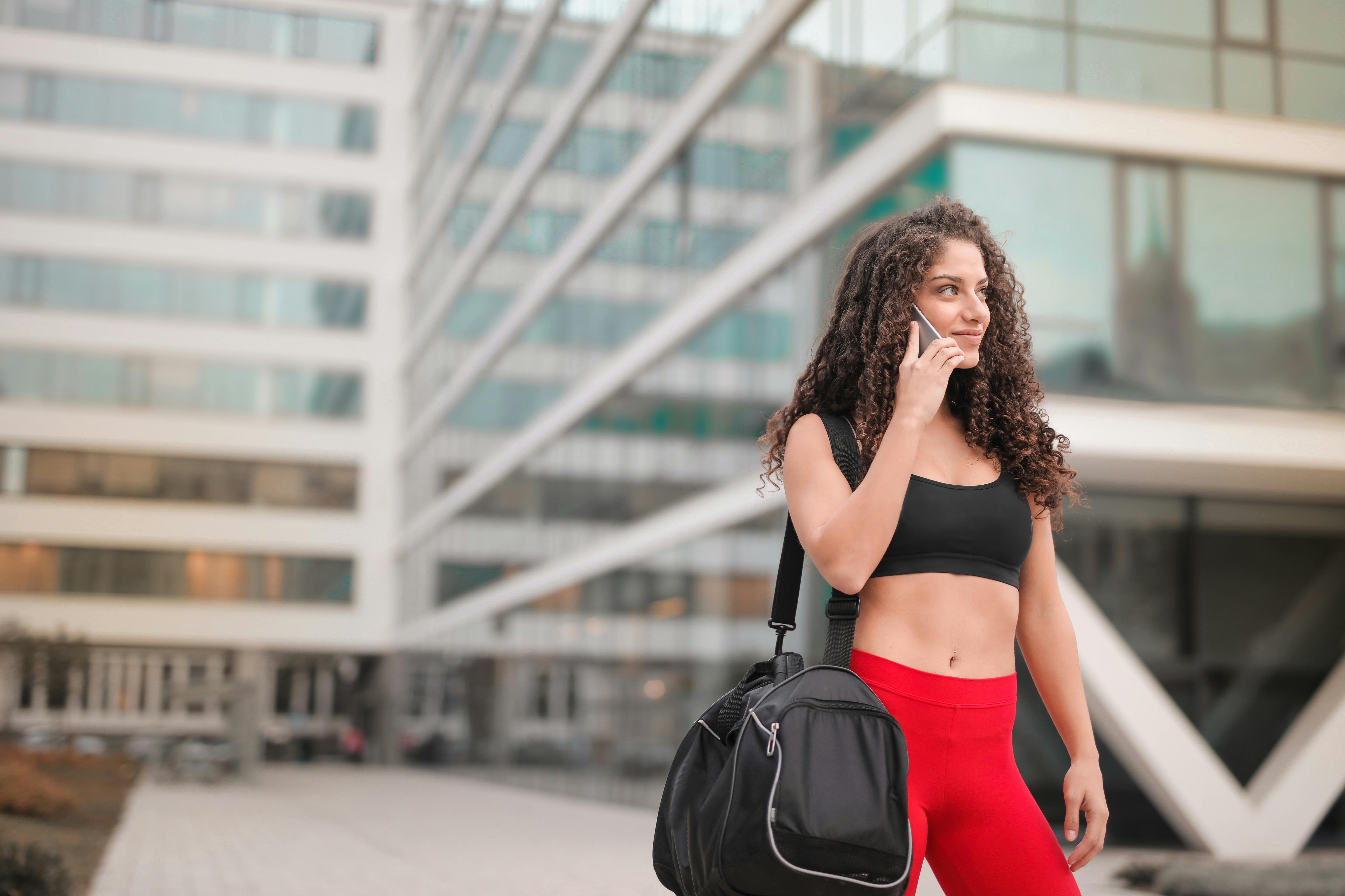 A woman in gym attire holding the phone close to her ear | Source: Pexels