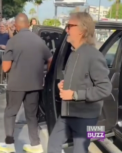Caught mid-turn beside the open car door, Paul McCartney appeared relaxed yet alert as he glanced towards the crowd. His understated outfit, combined with his now fuller beard and longer hairstyle, gave him a distinctly off-duty look, contrasting with the buzz of the moment around him. | Source: Facebook/IWMBuzz